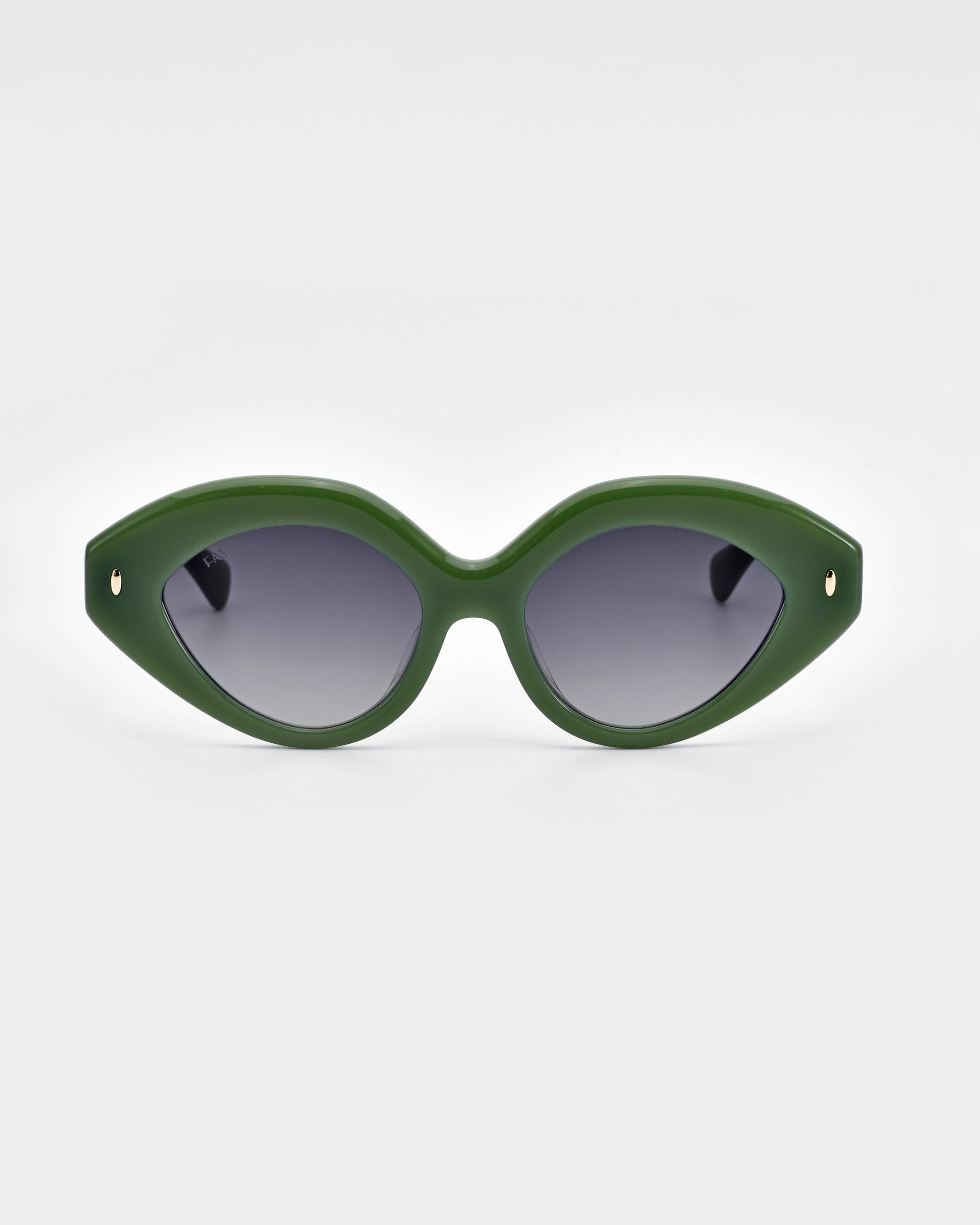 The Vera sunglasses by For Art's Sake® are displayed against a plain white background. These eco-friendly, green cat-eye frames feature bold and thick design with dark tinted lenses, complemented by small gold accents at the temples.