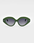 The Vera sunglasses by For Art's Sake® are displayed against a plain white background. These eco-friendly, green cat-eye frames feature bold and thick design with dark tinted lenses, complemented by small gold accents at the temples.