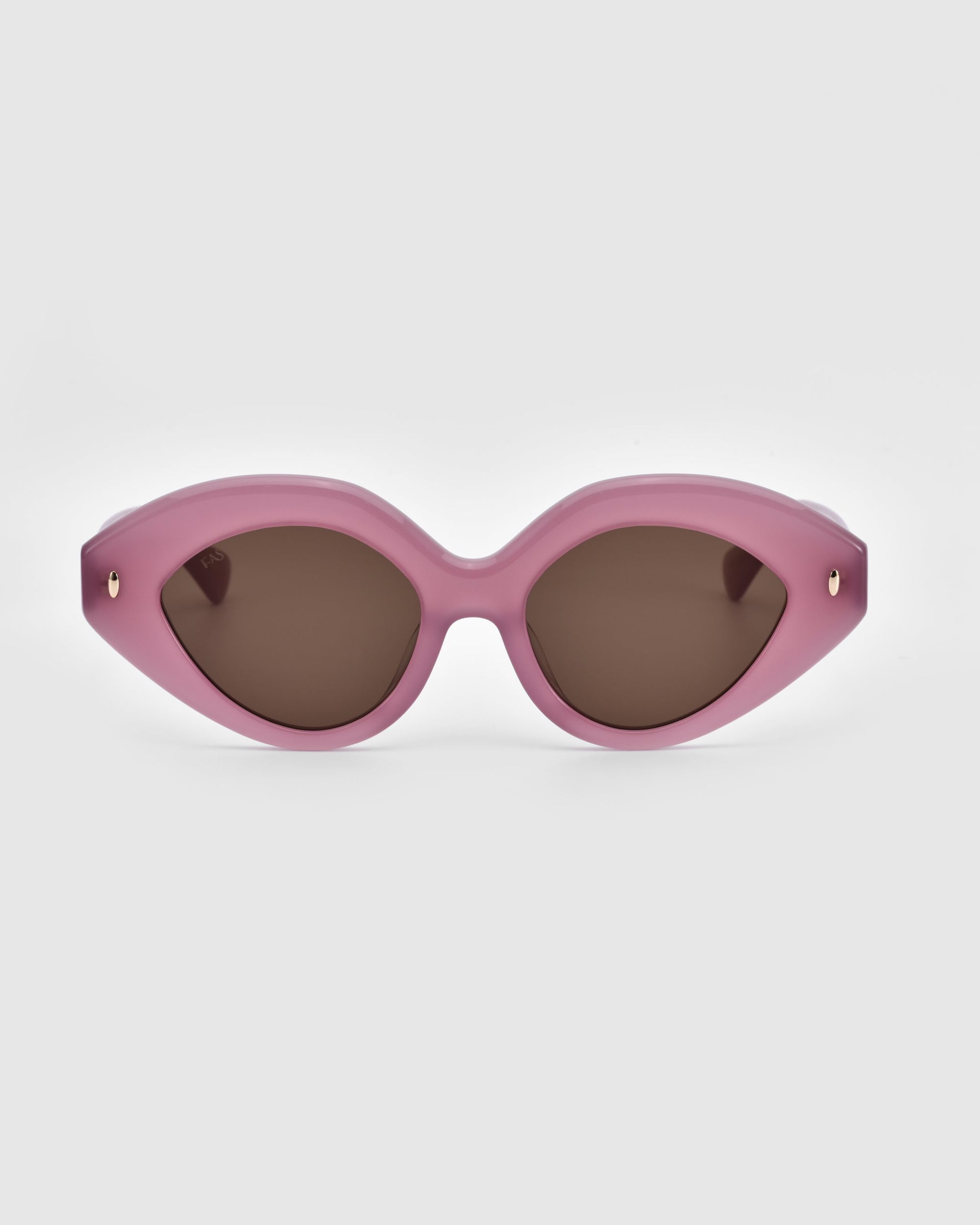 A pair of stylish, eco-friendly sunglasses called &quot;Vera&quot; by For Art&#39;s Sake® featuring a pink, cat-eye shaped frame and dark tinted lenses against a plain gray background. Small gold accents are visible on both sides of the frame near the hinges.