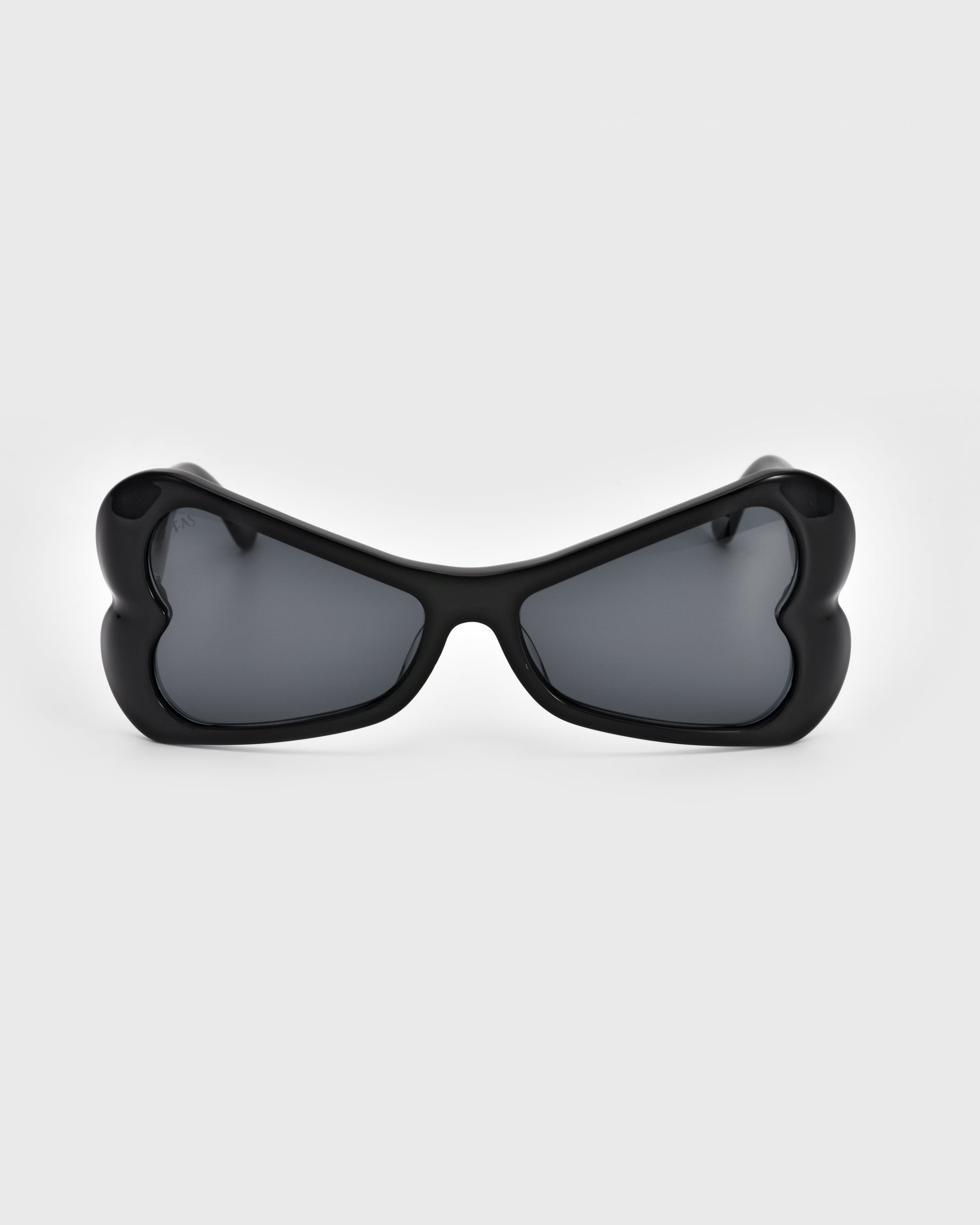 A pair of black Bubblegum sunglasses by For Art&#39;s Sake® featuring heart-shaped lenses made from sustainable materials. The dark lenses enhance the bold design, adding a whimsical twist to this classic accessory. The overall look is unique and playful, set against a plain white background.