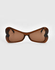 Bubblegum by For Art's Sake® features heart-shaped brown sunglasses with thick, dark brown frames and lightly tinted lenses. The plain, light-colored background highlights the eyewear's unique shape and bold design, crafted from sustainable materials.