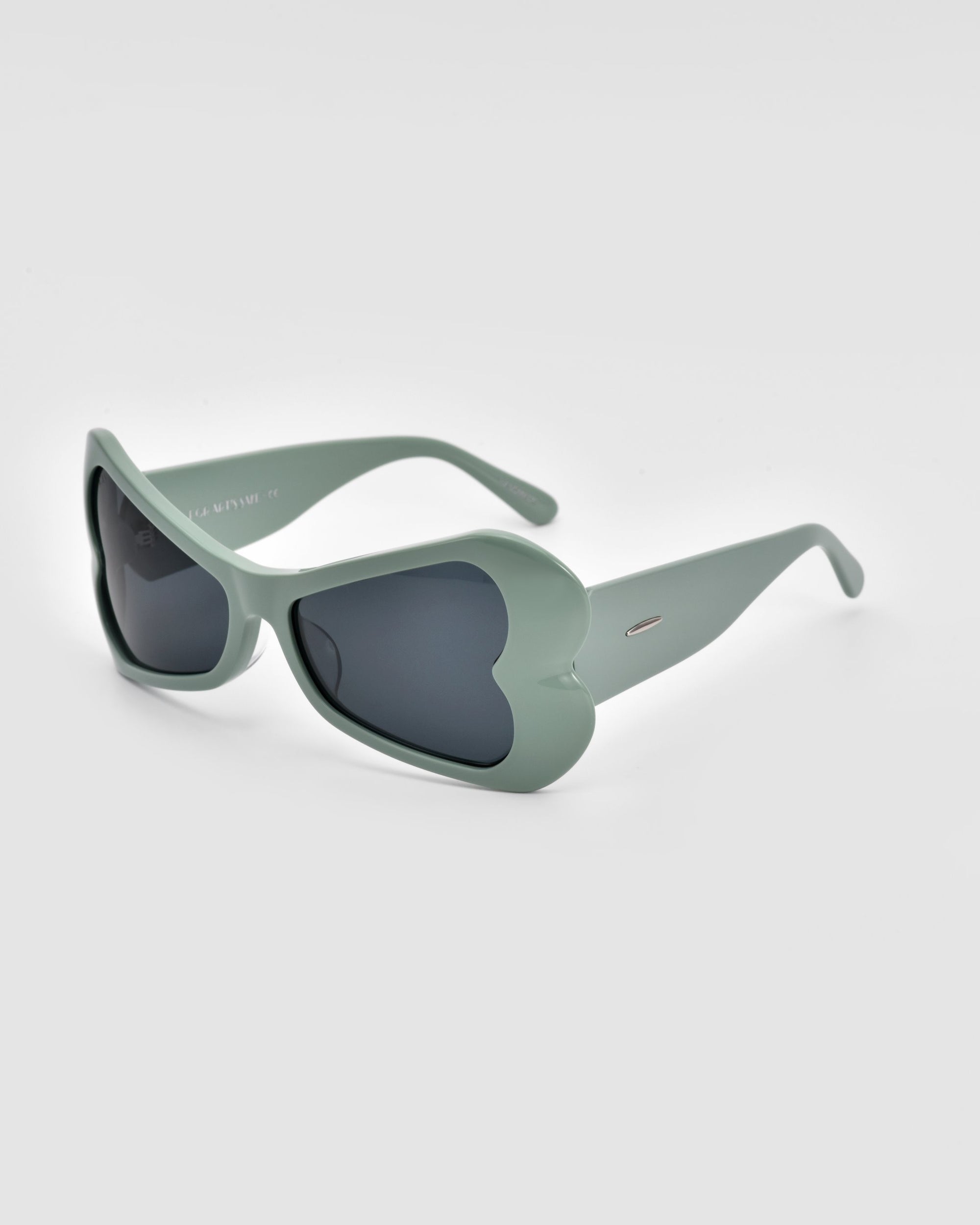 A pair of For Art's Sake® Bubblegum sunglasses, featuring heart-shaped mint green frames and dark tinted lenses, displayed on a plain white background.