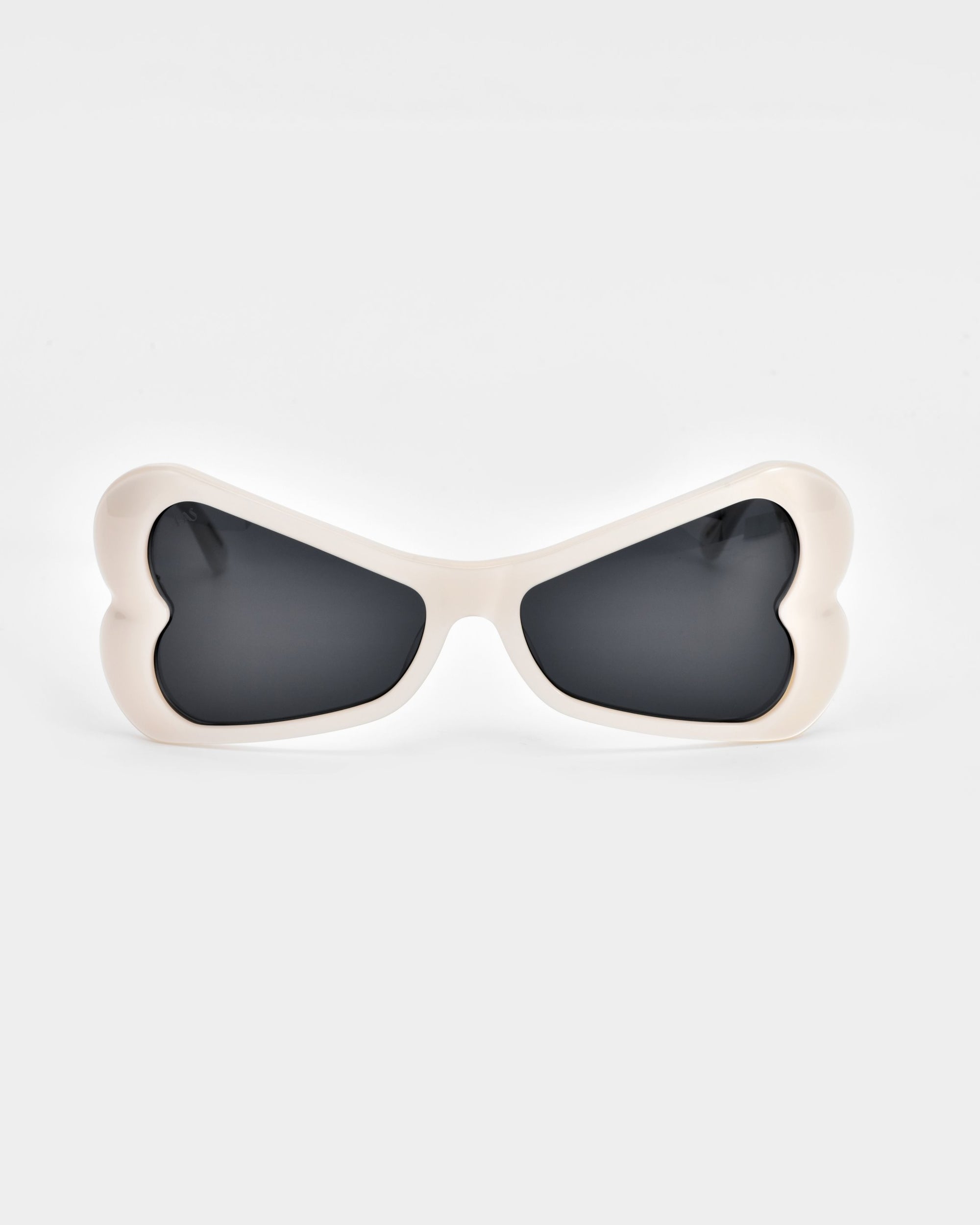 Bubblegum sunglasses by For Art&#39;s Sake® feature heart-shaped frames crafted from biodegradable acetate. The white frames with black lenses are set against a plain, light grey background.