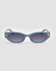 A pair of For Art’s Sake® Skinny Latte sunglasses with blue oval-shaped lenses. The frame, crafted from biodegradable acetate, is thick and solid-colored, featuring small decorative gold-colored accents near the hinges on both sides. The background is plain white.