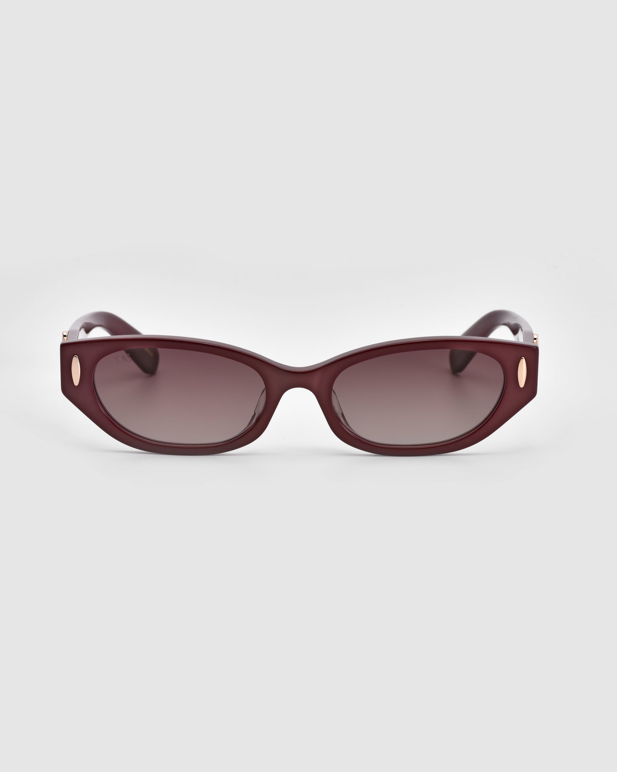 A pair of For Art's Sake® Skinny Latte sunglasses with dark burgundy rectangular frames featuring small gold accents and dark tinted lenses, crafted from biodegradable acetate, set against a white background.