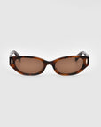 A pair of Skinny Latte sunglasses from For Art's Sake® with a rectangular shape, tortoiseshell frame, and dark brown lenses. Featuring a minimalist design with oval cut-out details near the hinges, these sunglasses are displayed against a plain white background.