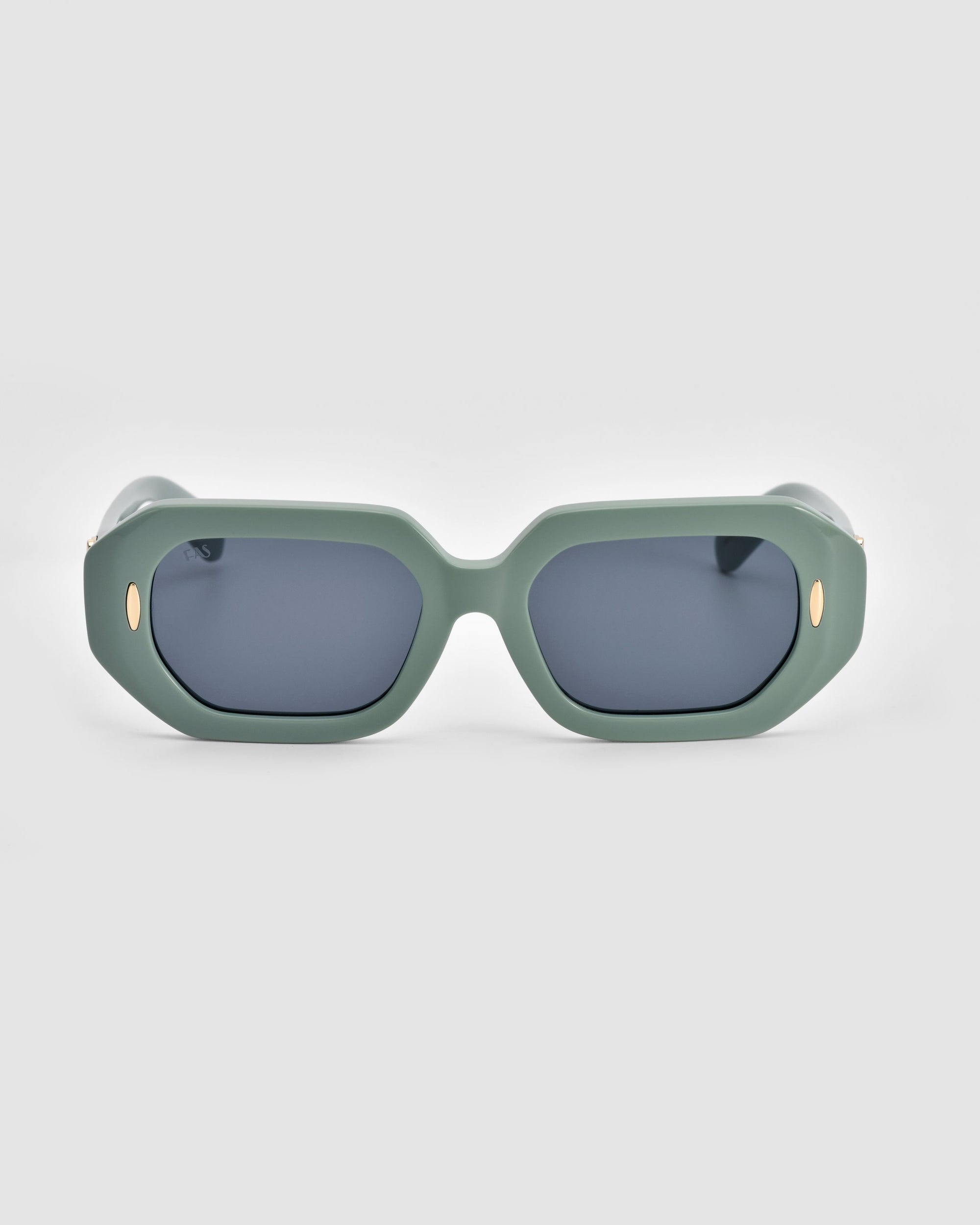 A pair of oversized For Art's Sake® Vitamin D sunglasses with thick, green rectangular frames and dark lenses. The temples feature small gold oval accents near the hinges, adding a touch of elegance. Made from stainless steel and biodegradable acetate, these stylish sunglasses are as eco-friendly as they are fashionable.