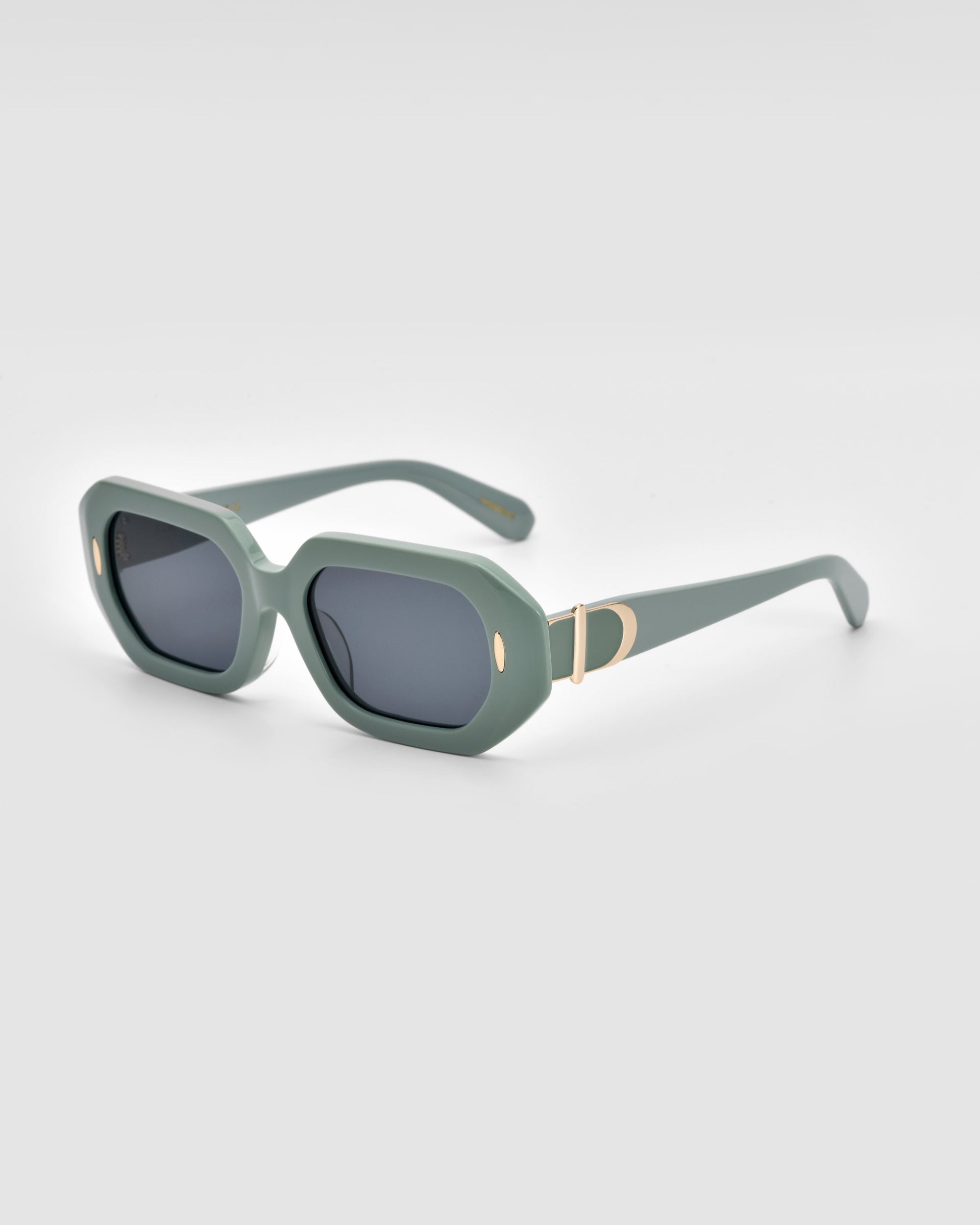 A pair of stylish, rectangular, green-framed Vitamin D sunglasses by For Art&#39;s Sake® with dark lenses. The sunglasses feature gold accents, including an oval gold detail on the front side of each temple and a larger gold &#39;D&#39; logo on the wide arms. The contemporary, sleek design is enhanced by an oversized frame for added flair.