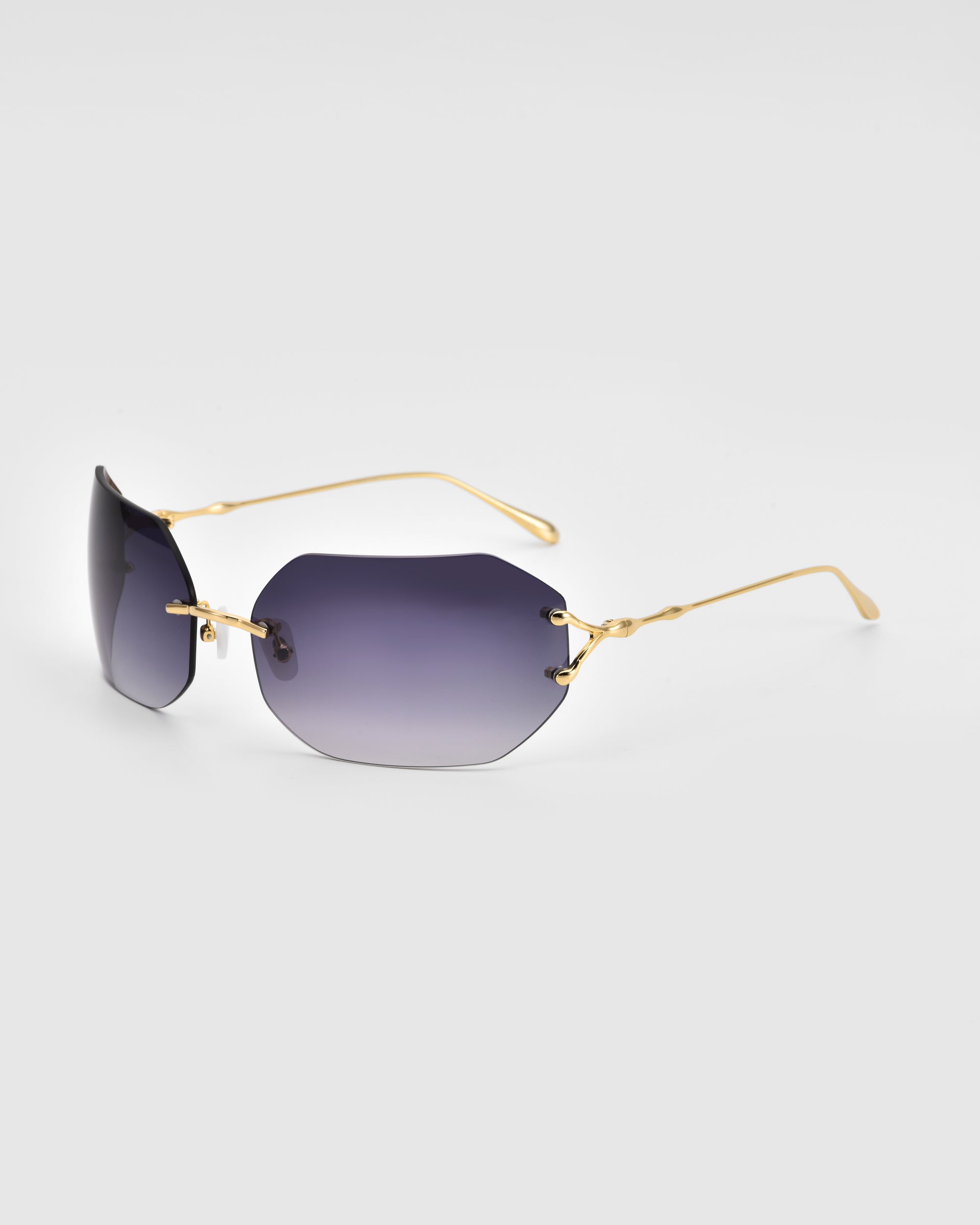 A pair of For Art's Sake® Hutton sunglasses featuring black gradient lenses and thin gold-colored frames. The frameless design embodies minimalist modern elegance and vintage glamour, elegantly showcased against a plain white background.