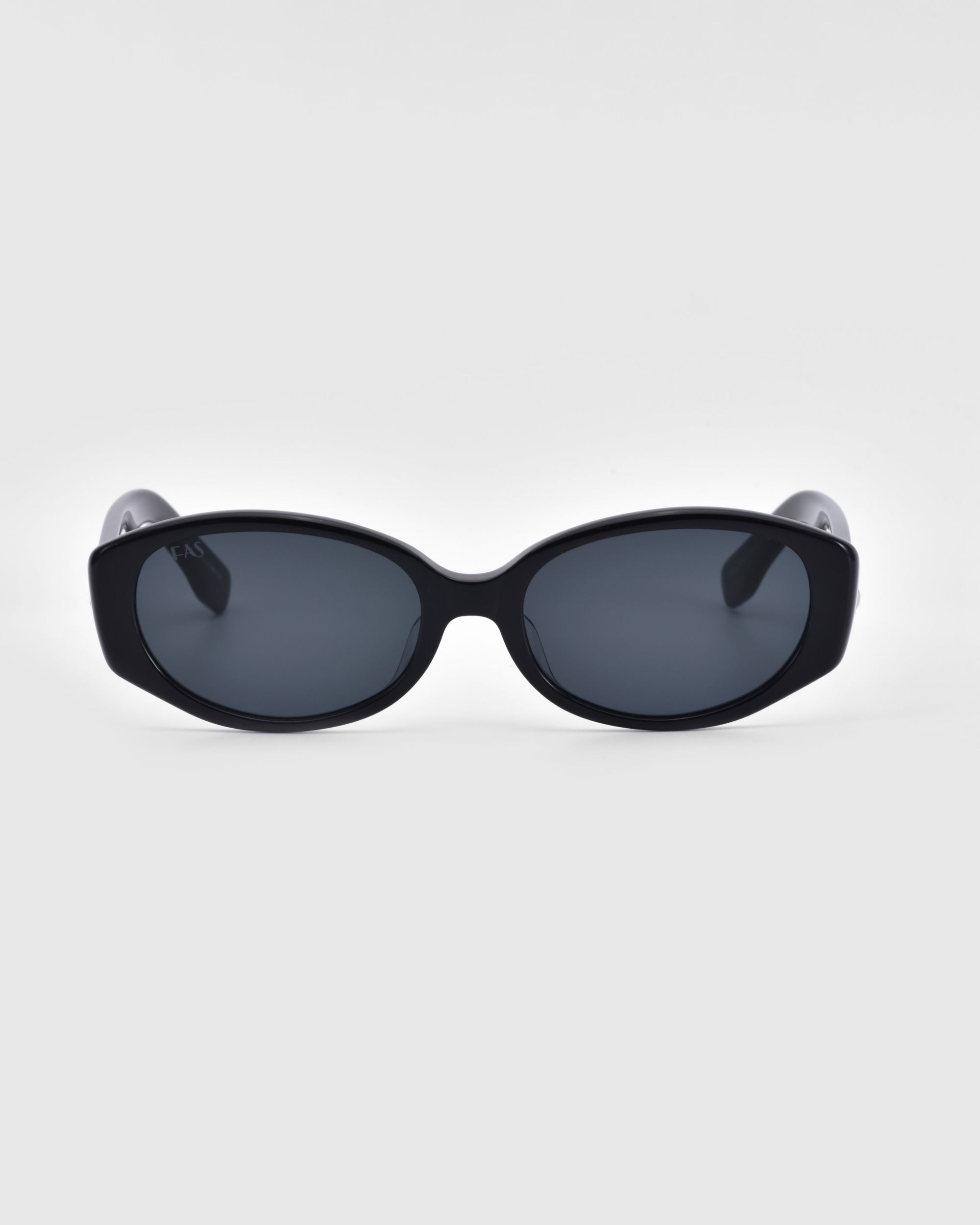 A pair of black oval-shaped sunglasses with dark lenses from For Art's Sake®, named Friday. The frame is solid black, providing a sleek and modern look. Featuring UV protection, the background is plain white, highlighting the simplicity and stylish design of these Friday sunglasses.