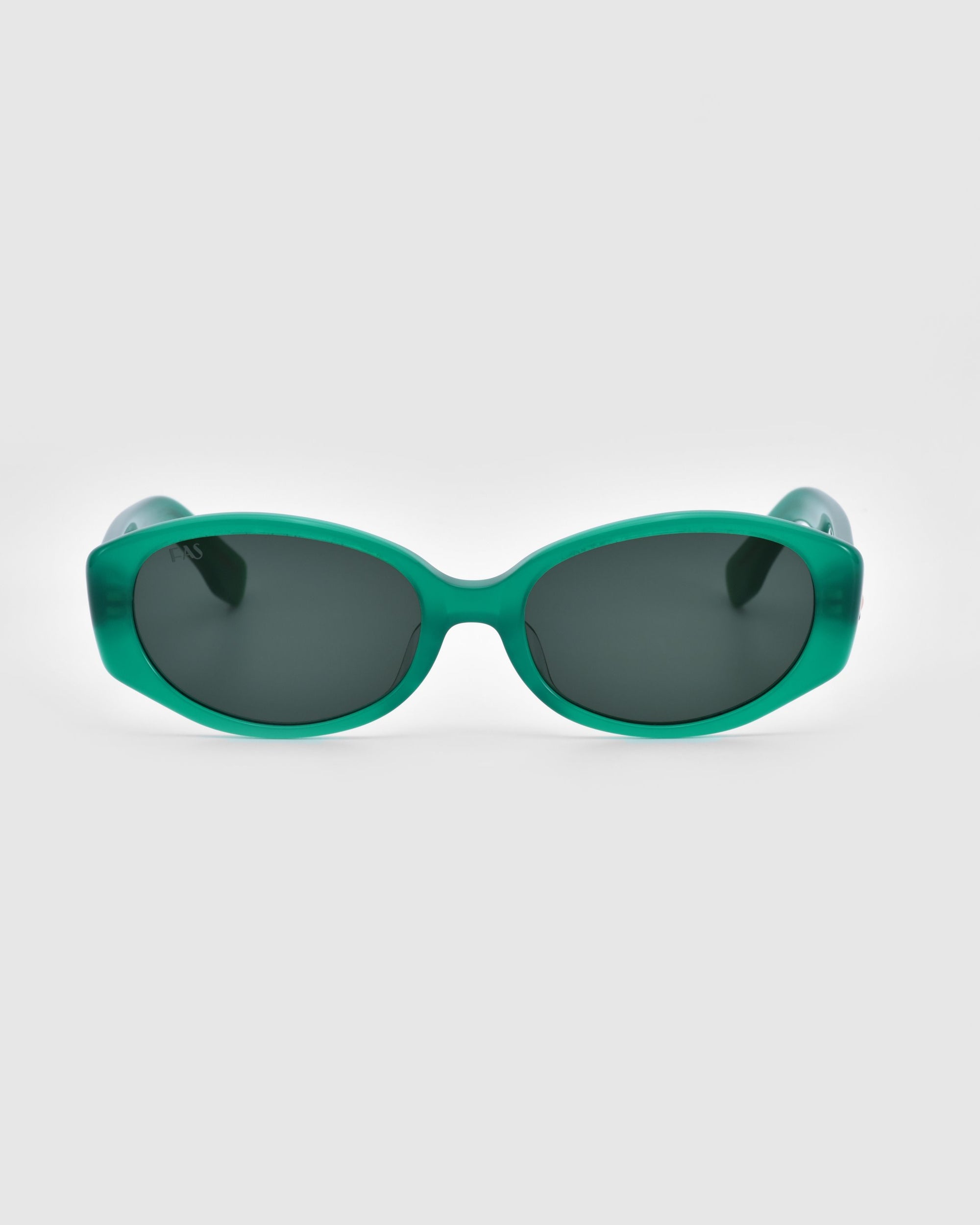 A pair of green, oval-shaped For Art's Sake® Friday sunglasses with dark-tinted lenses are displayed against a plain white background, offering chic geometric eyewear with premium UV protection.