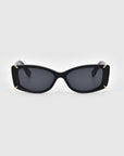 A pair of sleek, rectangular black Dyer sunglasses by For Art's Sake® with dark lenses and subtle gold accents at the corners. The design is modern and stylish, showcasing a minimalist aesthetic. Featuring UV protection, these luxury sunglasses are positioned facing forward against a plain white background.