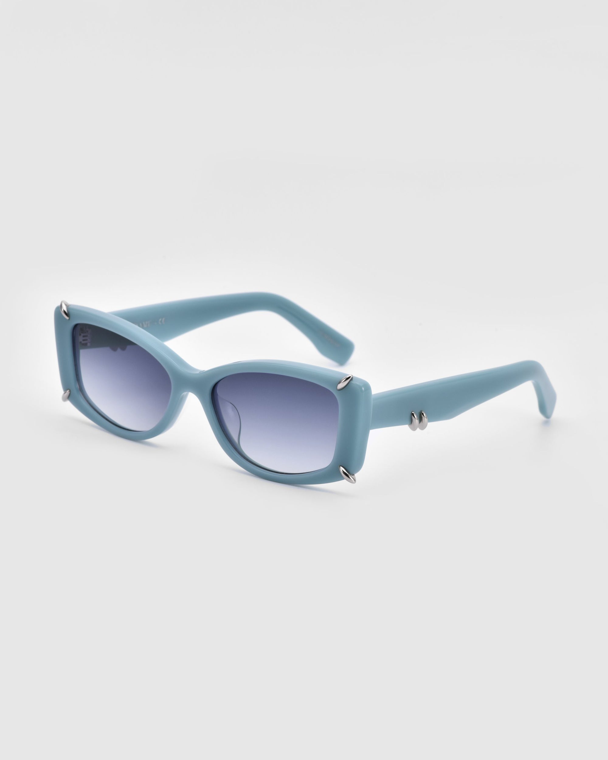 A pair of For Art's Sake® Dyer sunglasses with light blue rectangular frames and blue-tinted lenses. The frame features small silver screws at the front corners and a twisted silver detail on the temples, offering UV protection. Designed for luxury and sustainability, the backdrop is a plain white canvas.