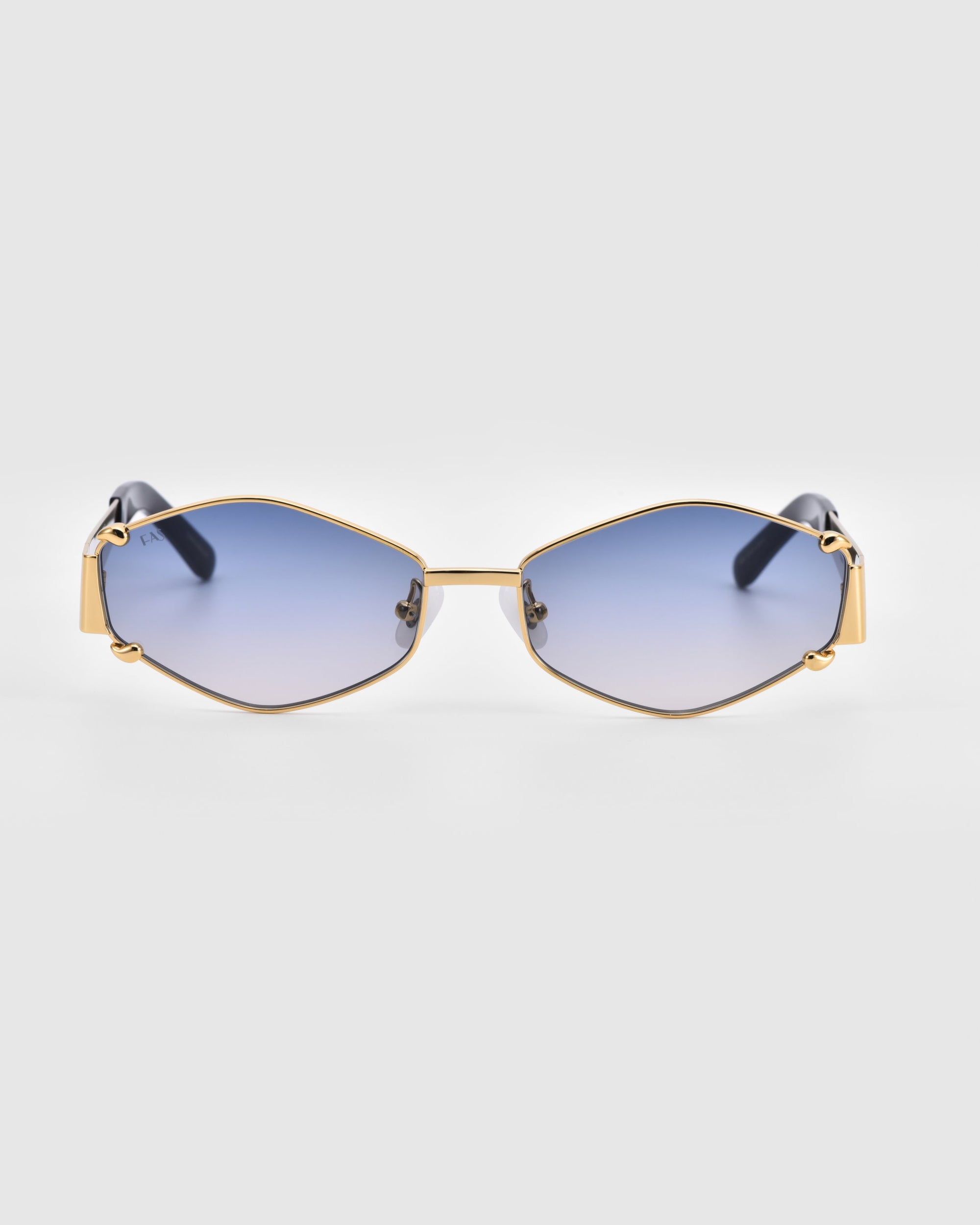 Introducing the For Art&#39;s Sake® Empress sunglasses: a pair of stylish luxury eyewear featuring oversized hexagonal gold frames and blue gradient lenses. These sunglasses offer UV protection and come with black temple tips for added comfort. The image is set against a plain white background.