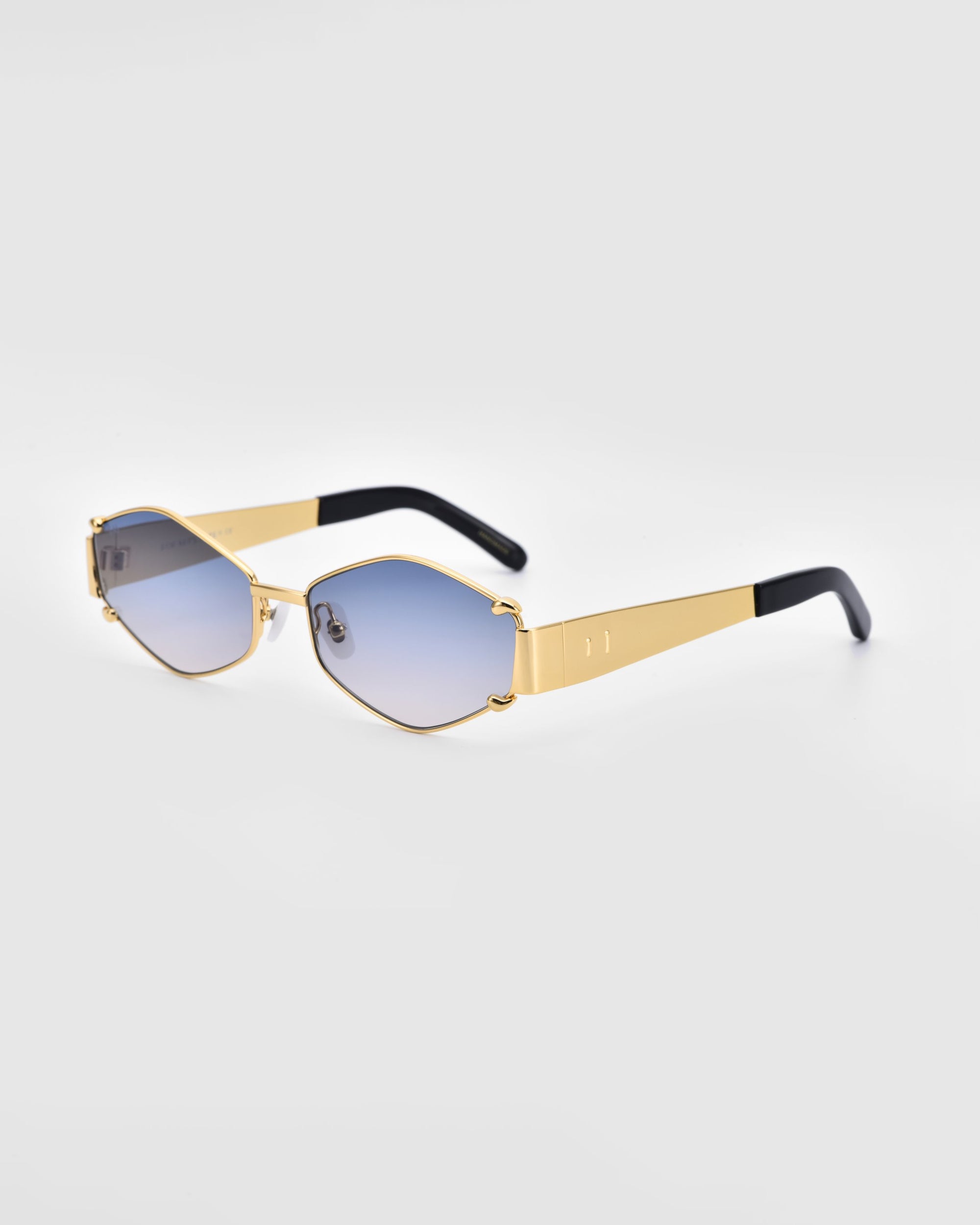 The &quot;Empress&quot; luxury sunglasses by For Art&#39;s Sake® feature stylish gold-colored frames with hexagonal blue lenses and black ear pieces, providing UV protection and a modern, trendy look against a plain white background.