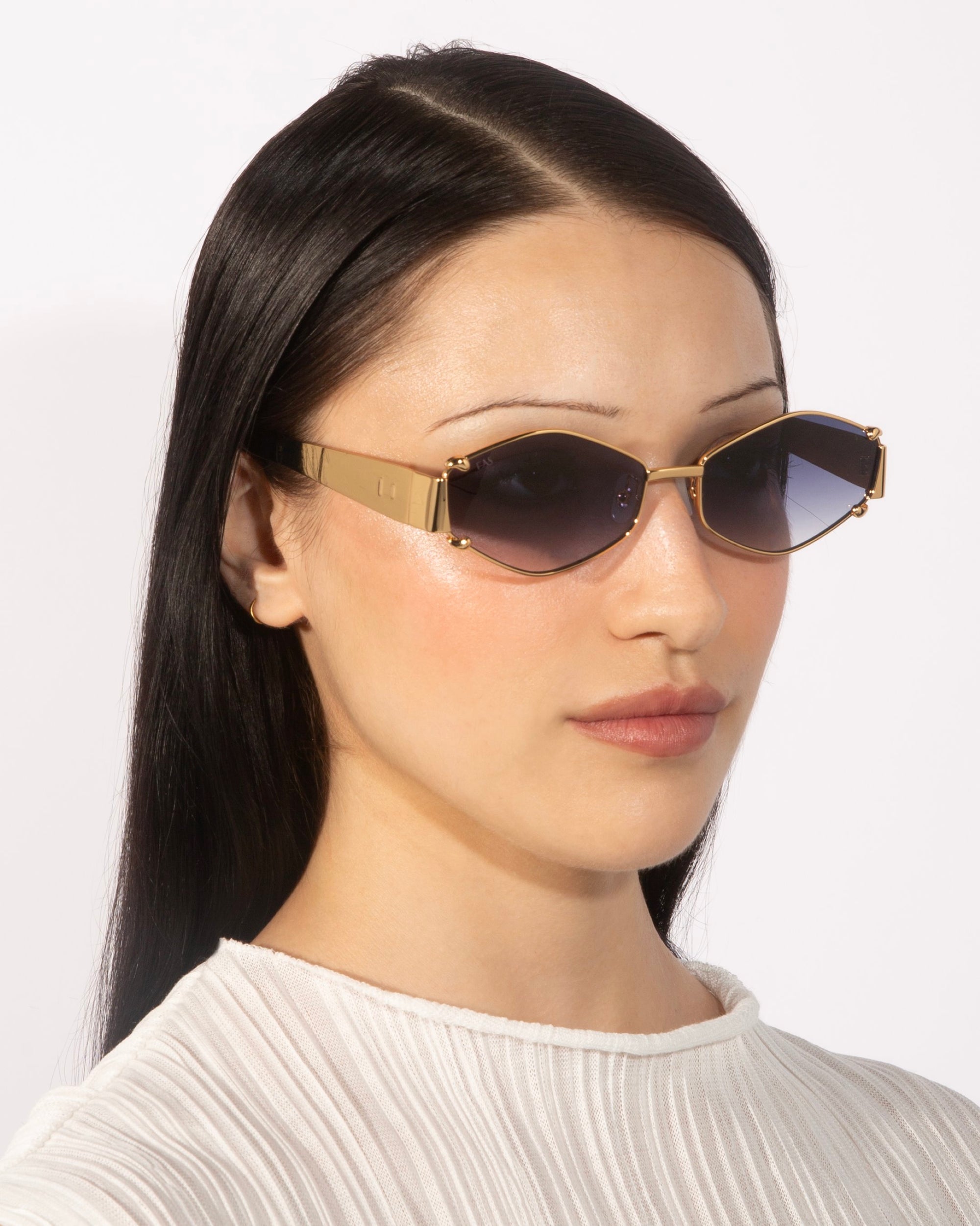 A person with long, straight black hair is wearing angular Empress sunglasses by For Art&#39;s Sake® with dark lenses and a white textured top. The oversized frame enhances the elegance of the luxury eyewear against a plain white background.