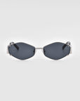 A pair of luxury, geometric Empress sunglasses by For Art's Sake®, featuring hexagonal dark lenses and a metallic frame, is centered against a plain white background. The modern and stylish design boasts sleek lines and minimalistic detailing, offering premium UV protection for discerning tastes.