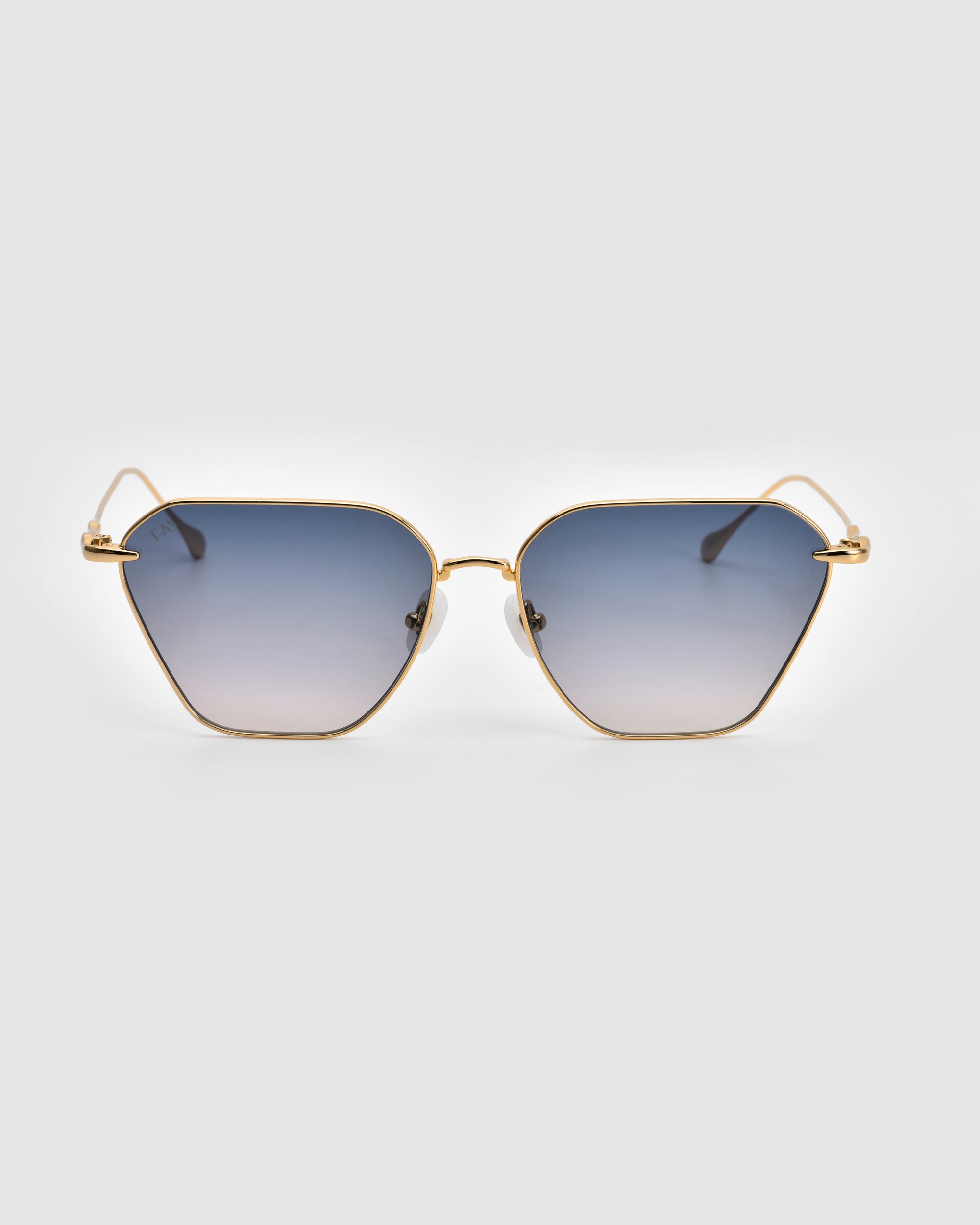 The For Art&#39;s Sake® Cece Sunglasses are characterized by their gold metal frames and blue gradient lenses. These lenses exhibit a subtly hexagonal geometric shape, complemented by thin, straight arms that terminate in clear plastic tips. Displayed against a plain white background, the Cece Sunglasses exude both style and sophistication.