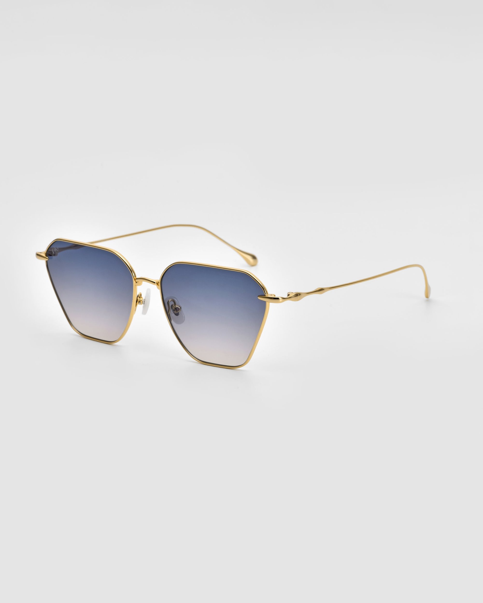 A pair of stylish For Art&#39;s Sake® Cece Sunglasses with gold frames and blue gradient lenses is shown against a plain white background. The thin metal temples and nose pads, paired with subtle geometric shapes, add a sleek, elegant touch to the design.