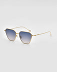 A pair of stylish For Art's Sake® Cece Sunglasses with gold frames and blue gradient lenses is shown against a plain white background. The thin metal temples and nose pads, paired with subtle geometric shapes, add a sleek, elegant touch to the design.