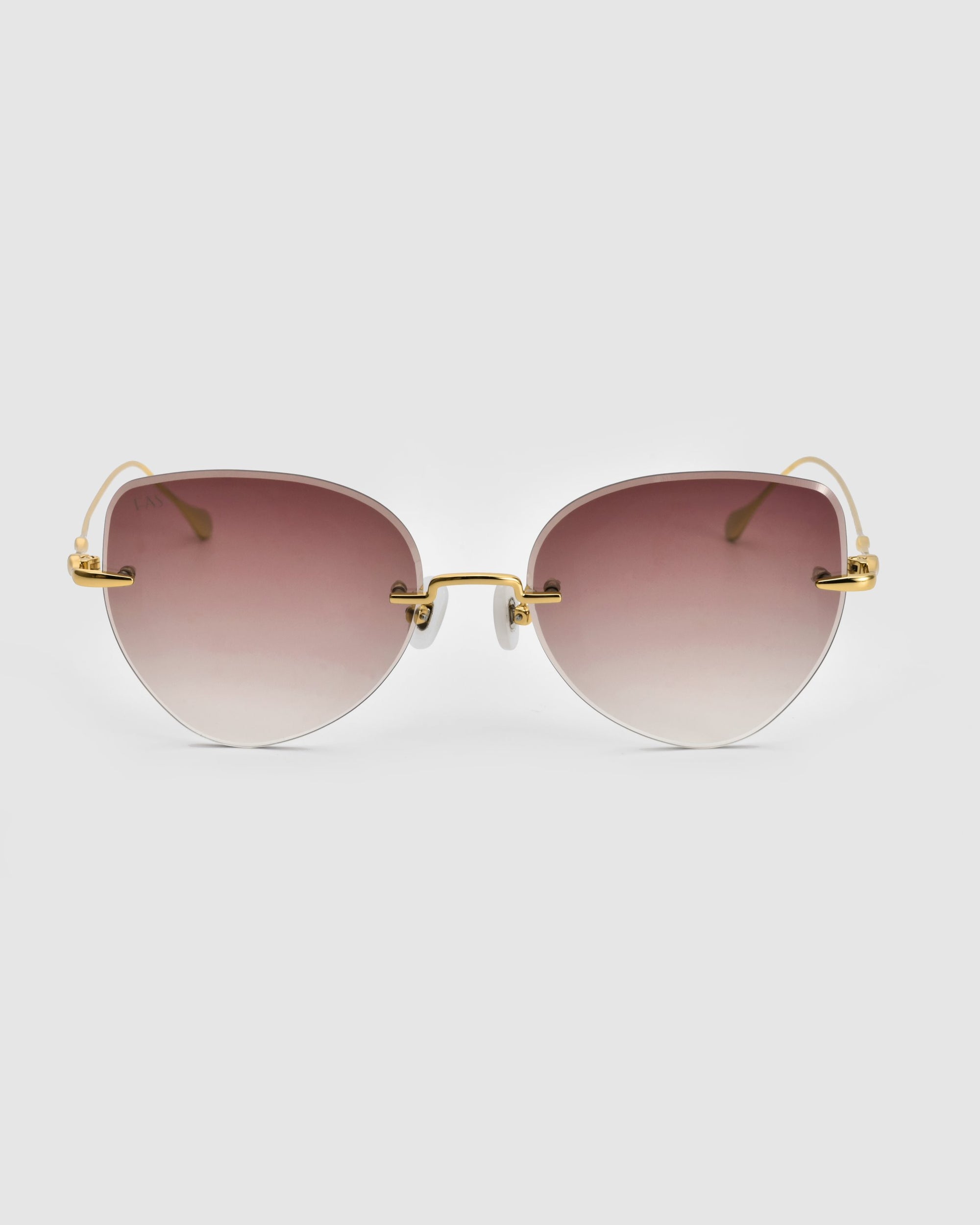 A pair of stylish For Art&#39;s Sake® Fifi Sunglasses featuring rimless, gradient lenses that transition from brown at the top to clear at the bottom. The cat-eye frameless design boasts 18k gold plating on the metal frames and slender temples. They are set against a clean, white background.