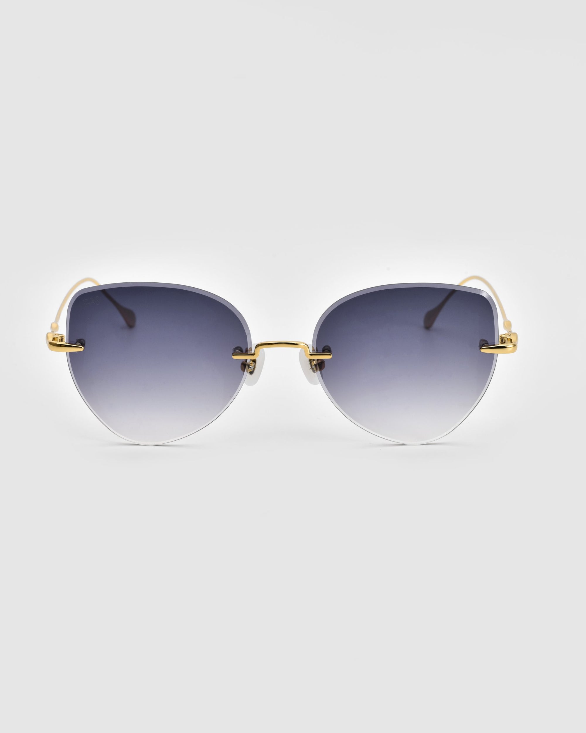 A pair of chic Fifi sunglasses from For Art&#39;s Sake®, featuring an elegant cat-eye frameless silhouette and 18k gold plating, is displayed against a plain white background. The modern design includes thin arms and minimalistic nose pads, exuding sophistication.