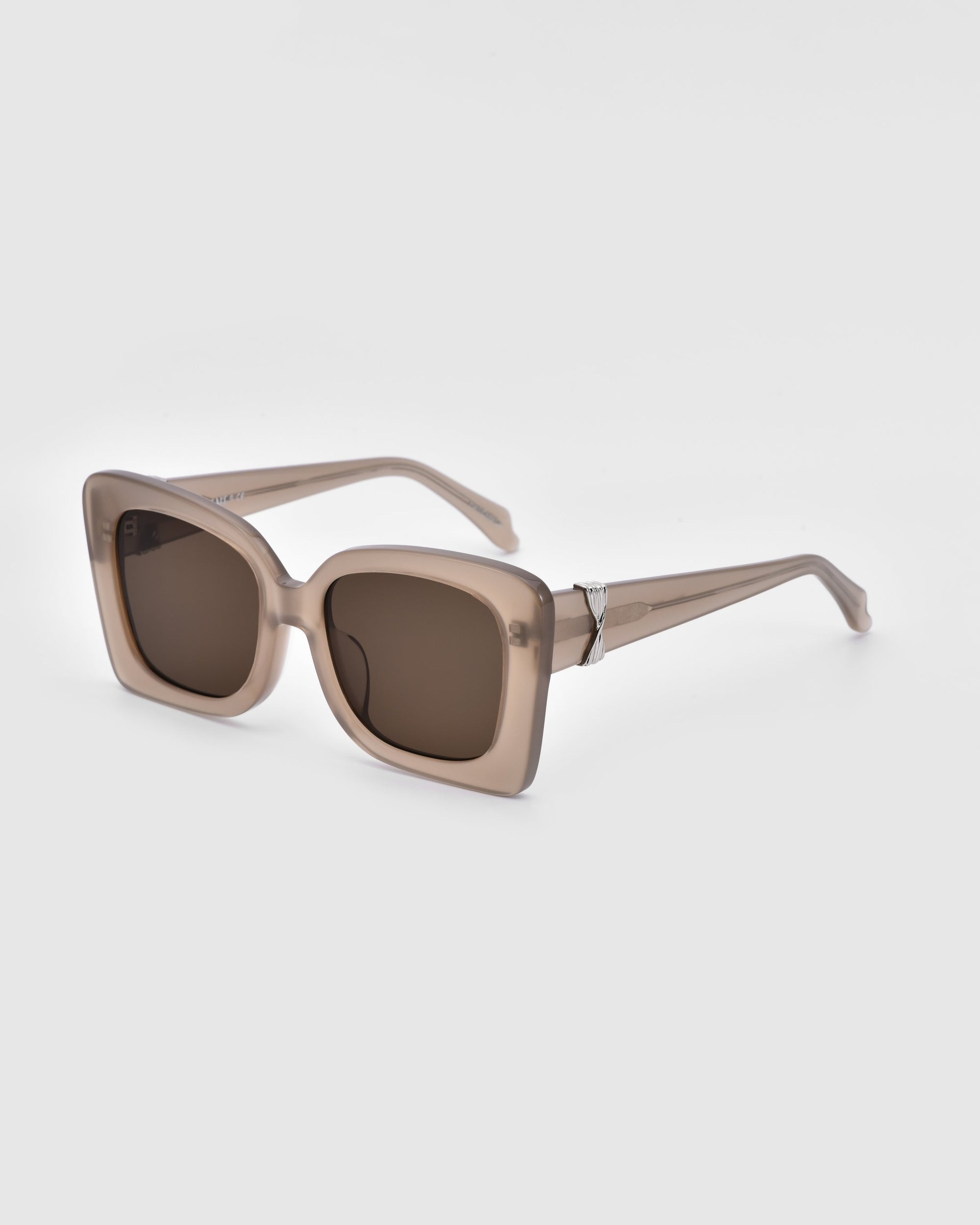 A pair of Ribbon sunglasses from For Art&#39;s Sake® in beige square frames with brown lenses set against a plain white background. The stylish accessory boasts a sleek design with slightly rounded edges, and the temples taper towards the ends.