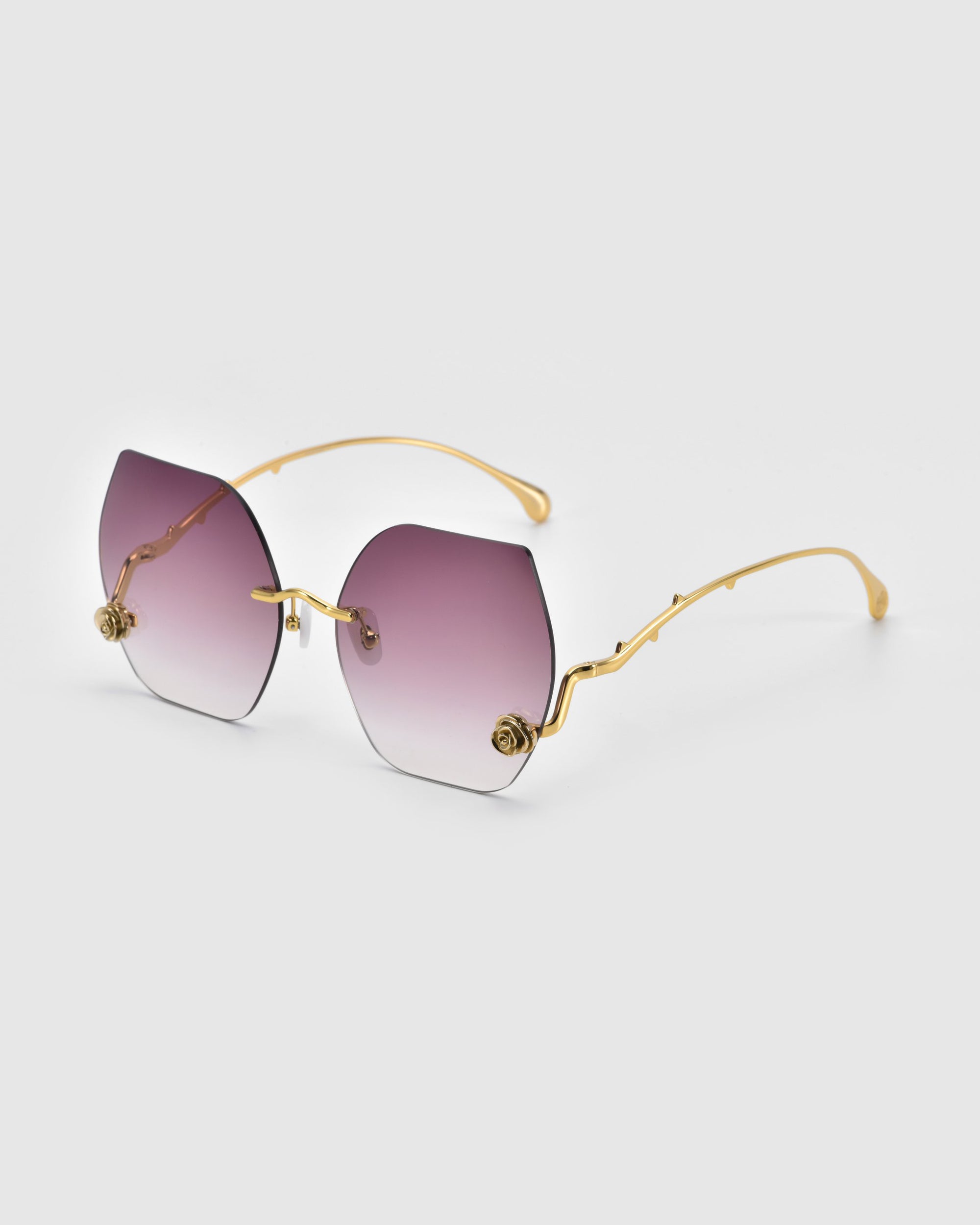 Part of For Art's Sake®'s La Vie En Rose collection, these gold-framed sunglasses feature gradient lenses from dark purple to clear, with ornate floral details at the corners. They're set against a plain white background.