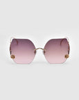 From the Rose Garden Collection, the "La Vie En Rose" sunglasses by For Art's Sake® showcase oversized frameless gradient pink lenses with gold rose ornaments at each corner, complemented by a gold nose bridge and temples against a light gray backdrop.