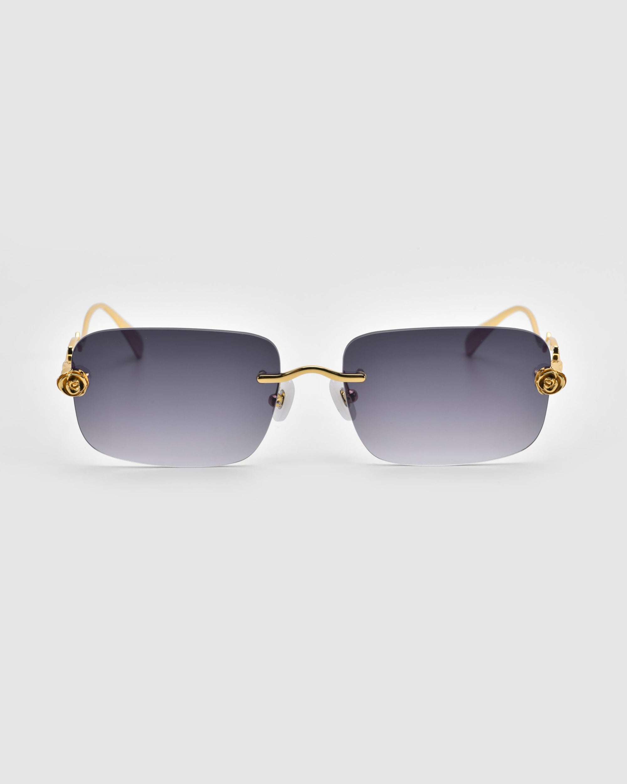 From the Rose Garden Collection by For Art's Sake®, these rectangular sunglasses feature oversized frameless dark gray gradient lenses and gold-toned temples with intricate swirl designs near the hinges, exuding elegance against a plain white background.