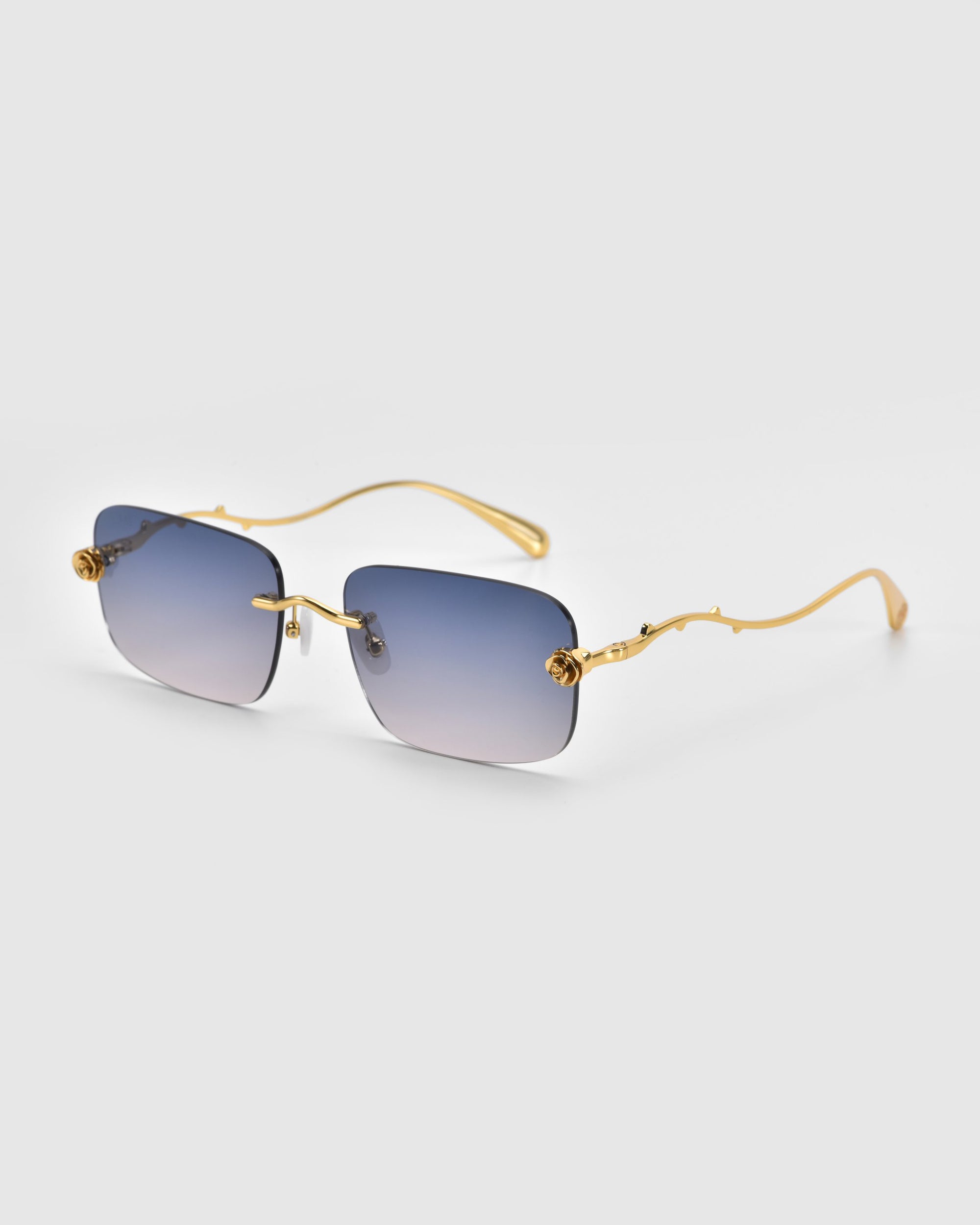 For Art's Sake® Rose Garden sunglasses feature gold frames and rectangular blue-tinted lenses on a white background, with temples showcasing a wavy design adorned with detailed sculpted rose ornaments near the hinges.