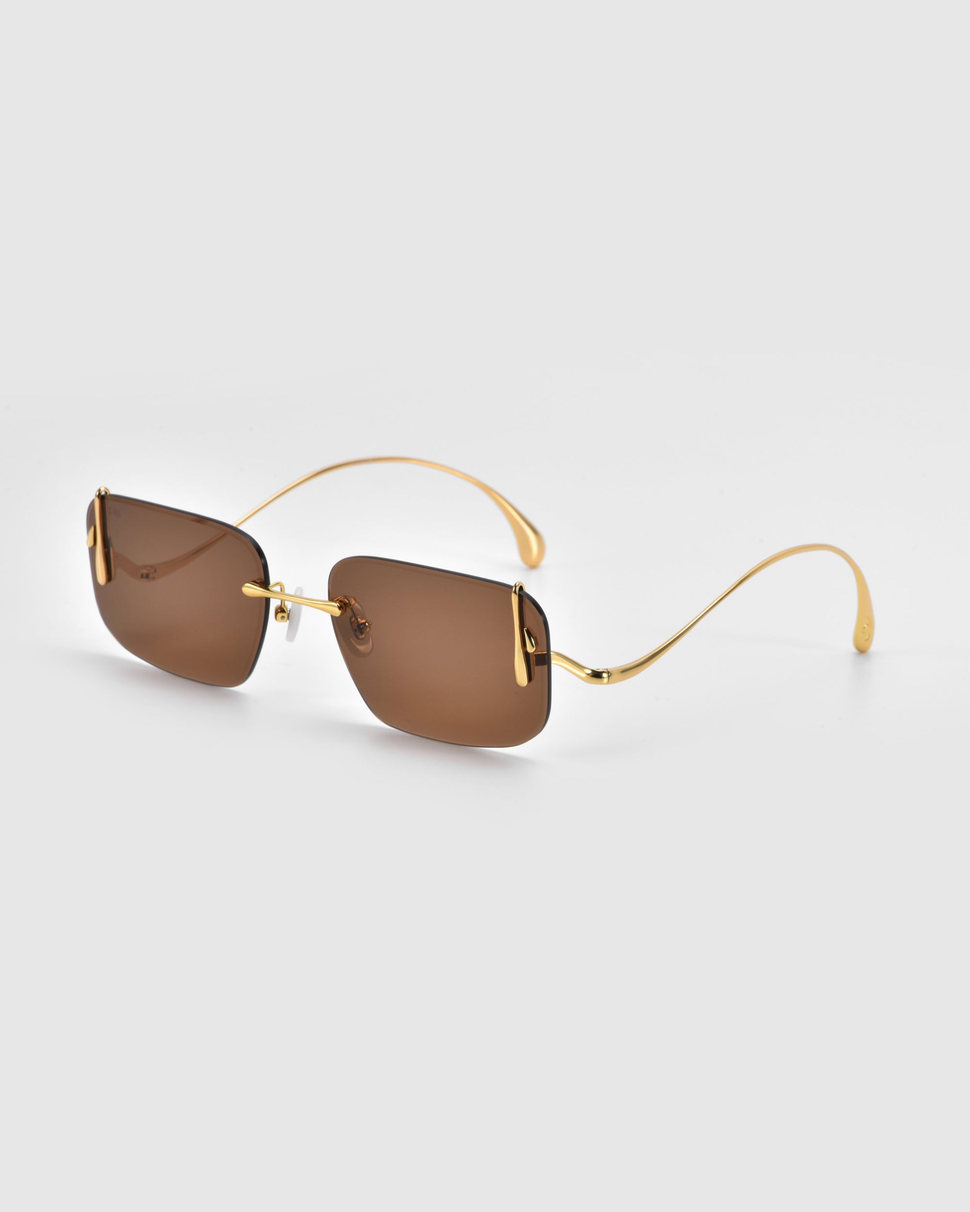 The Vermilion by For Art's Sake® are rectangular, rimless sunglasses boasting brown lenses and thin gold metal arms, set against a light gray background to highlight their sophisticated silhouette.