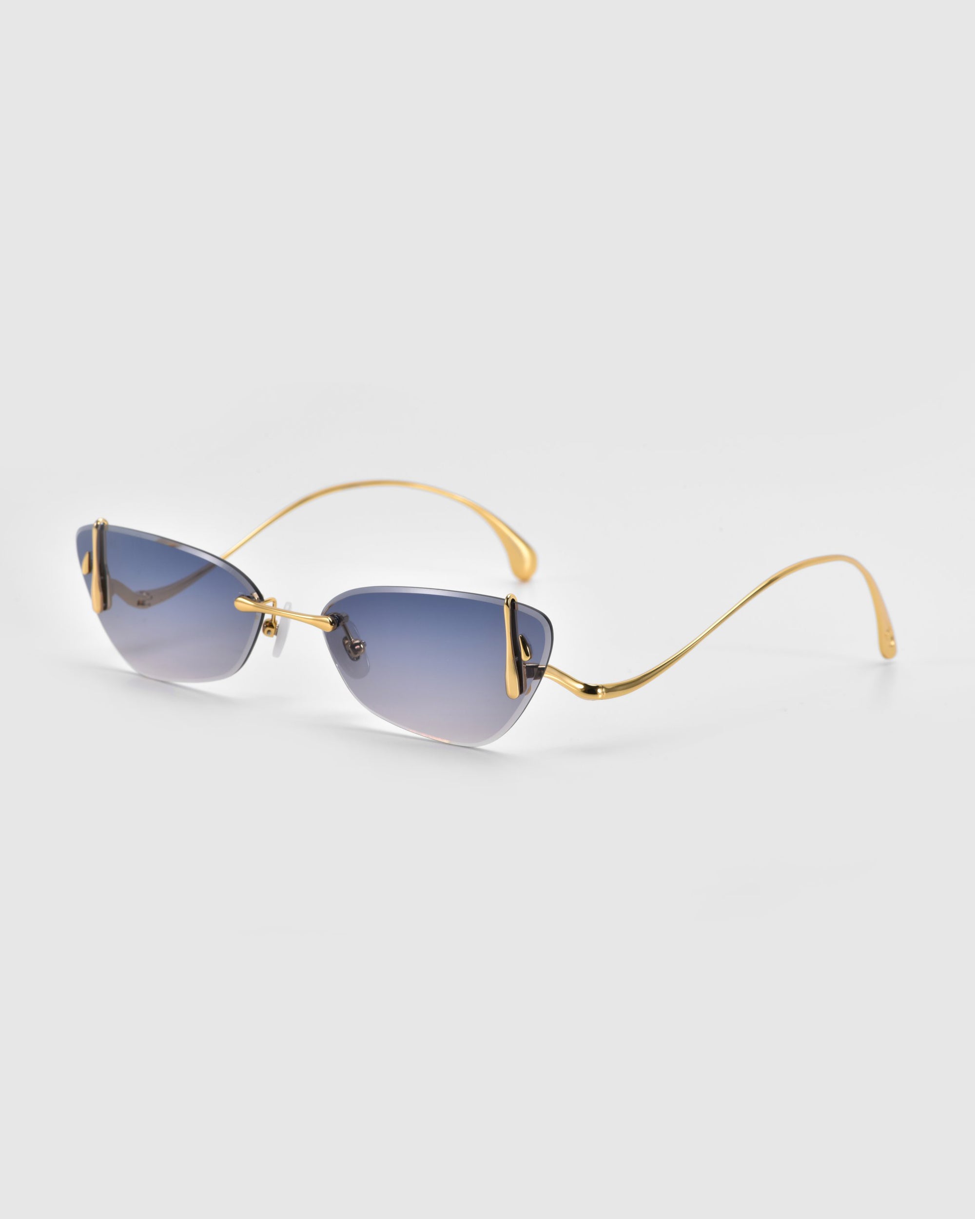 Part of For Art's Sake®'s Crimson Rose Garden Collection, these sunglasses feature rectangular blue-tinted lenses and slim gold metal frames, elegantly complemented by sculpted rose ornaments against a light gray background.