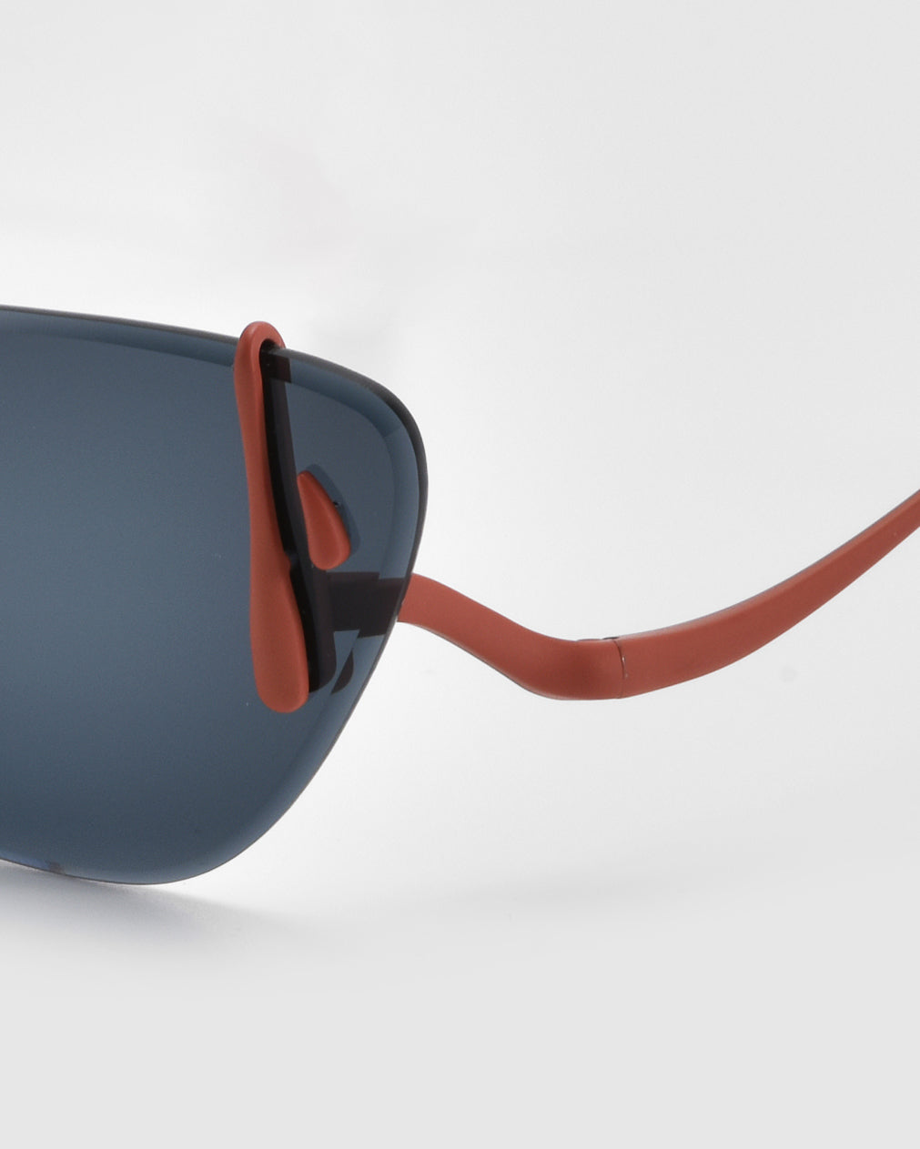 Close-up of For Art&#39;s Sake® Crimson sunglasses, showcasing dark blue lenses and orange temples. This lightweight eyewear features a sleek frame with gently curved earpieces against a smooth white background.