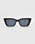 Dusk sunglasses by For Art's Sake® feature black square frames, dark lenses, and signature temples gracefully placed on a light gray background.