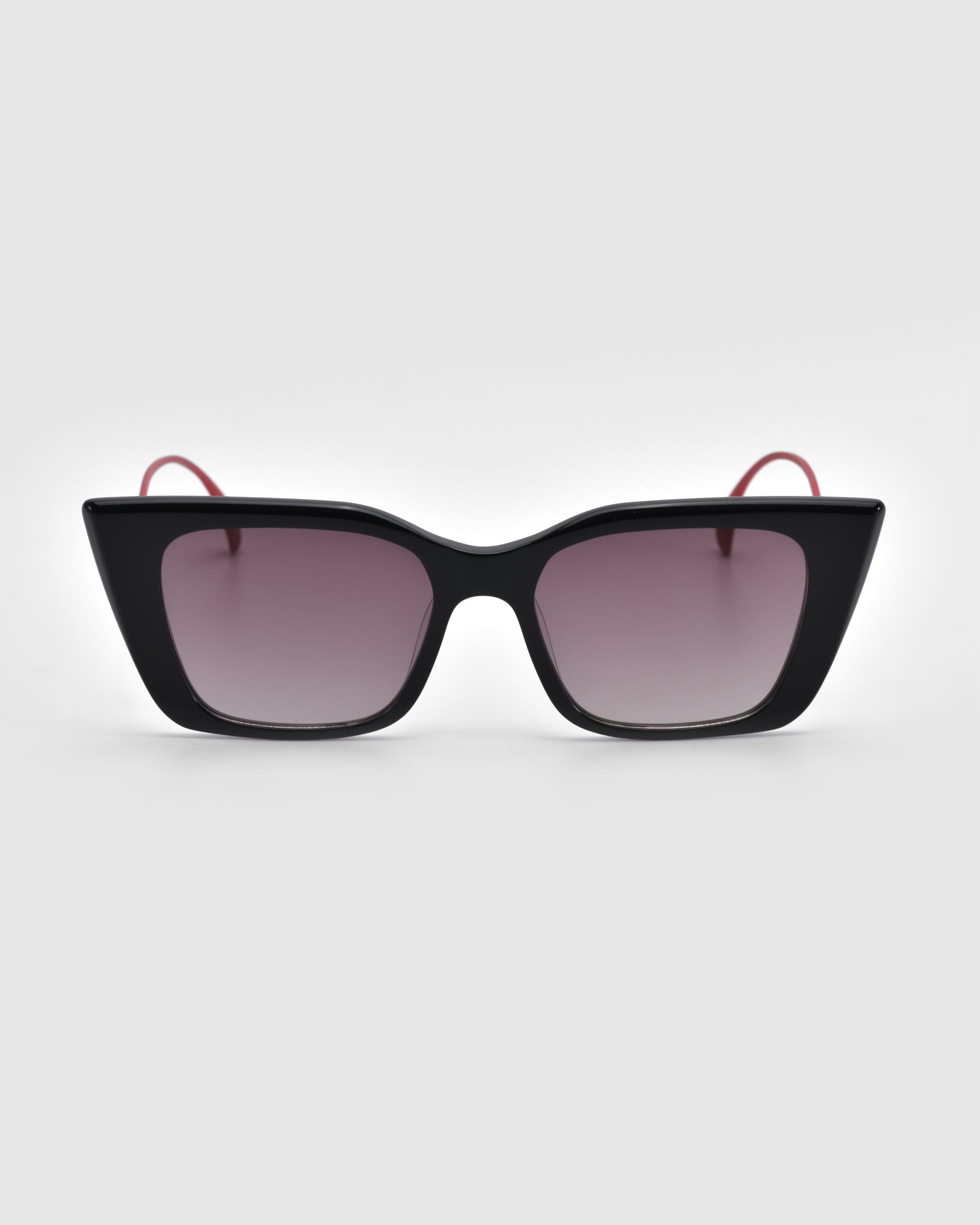 The Dusk sunglasses by For Art's Sake® feature a black cat-eye silhouette with gradient lenses, signature red temple arms, and an elegant acetate frame, displayed on a white background.