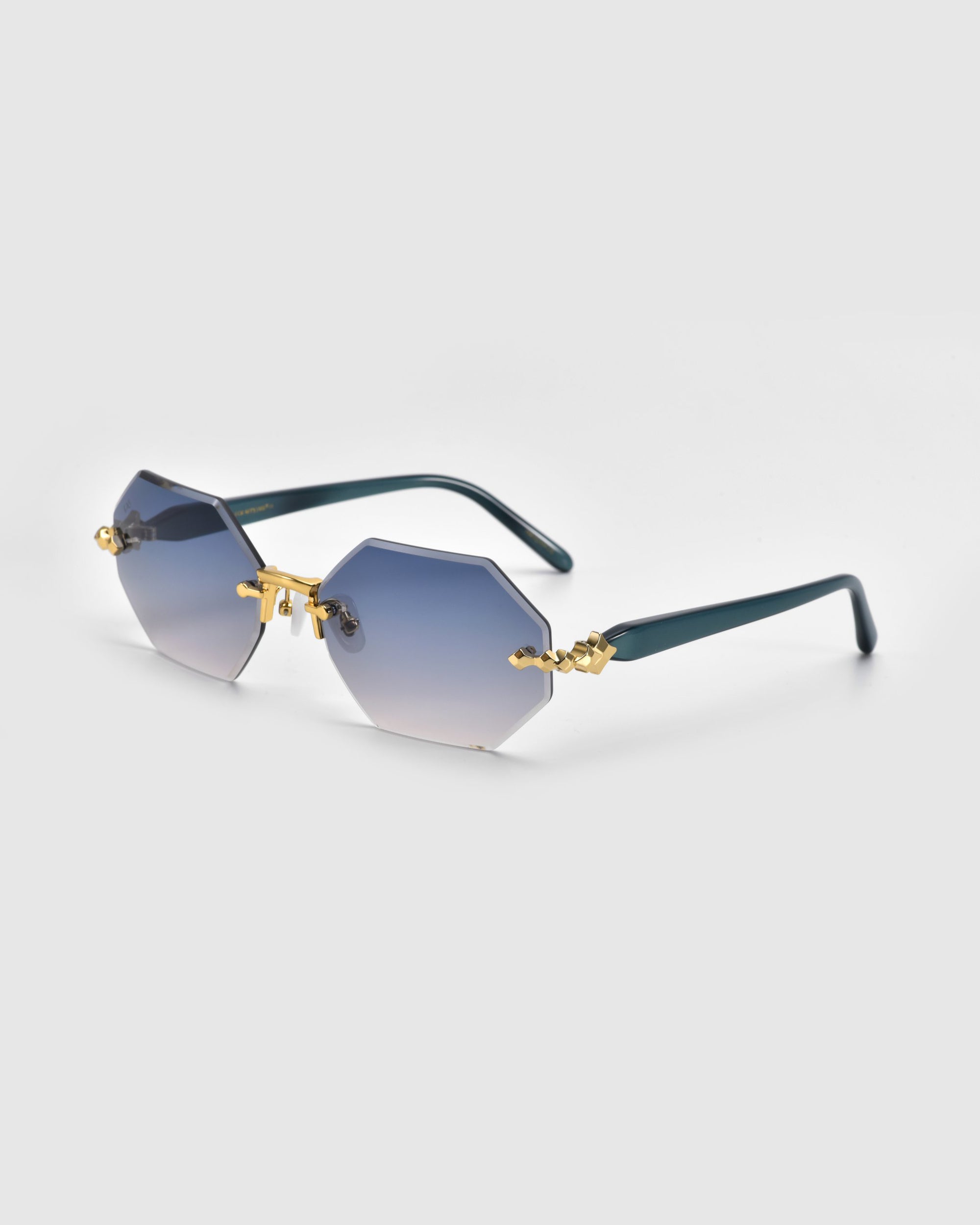 For Art's Sake® Haze sunglasses have octagonal gradient blue lenses, gold metal accents, and dark green arms for a stylish contrast. Part of the Rose Garden collection, they are set against a plain white background.