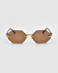 For Art's Sake® presents the 'Haze': hexagonal sunglasses with brown lenses, gold metal frames, and elegant temple decorations, shown from the front against a plain white background.