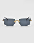 The Edith sunglasses from For Art's Sake® feature a sleek, frameless design with dark rectangular lenses and gold accents on the temples, set against a plain white background.