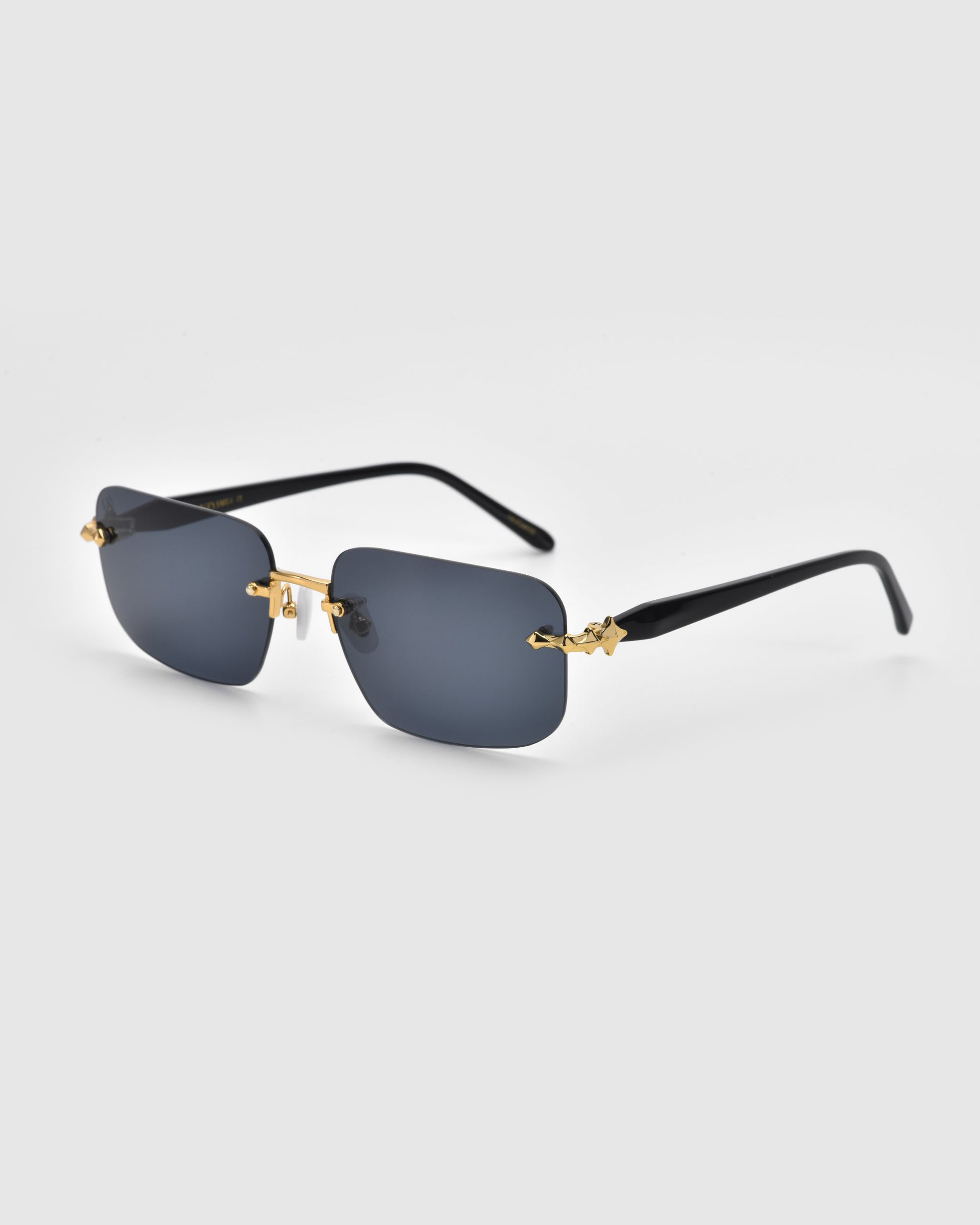 Part of the Rose Garden collection, For Art's Sake® Edith sunglasses feature a modern look with rectangular dark-tinted lenses and gold accents on the bridge and temples. Thin black arms enhance their sleek design against a light gray background.