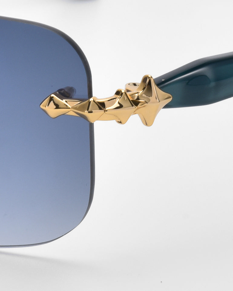 Close-up of For Art's Sake® Edith sunglasses showcasing soft rectangular blue-tinted lenses with a distinctive gold star-shaped frame hinge design. From the Rose Garden collection, the glossy dark-colored frame delivers a timeless classic style to this chic eyewear.