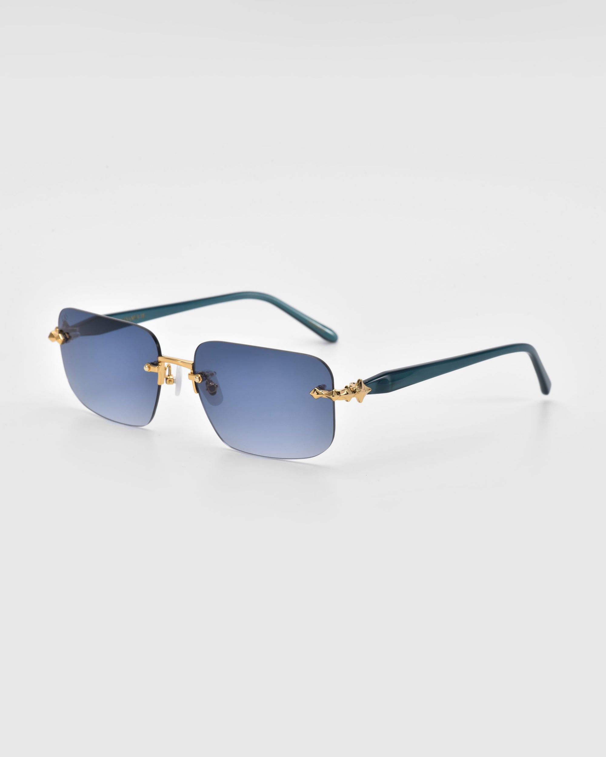 Part of the Edith collection from For Art's Sake®, these rimless sunglasses boast blue gradient rectangular lenses, gold-toned bridges, and dark green arms, evoking falling stars on a serene night sky. Displayed on a light gray background.