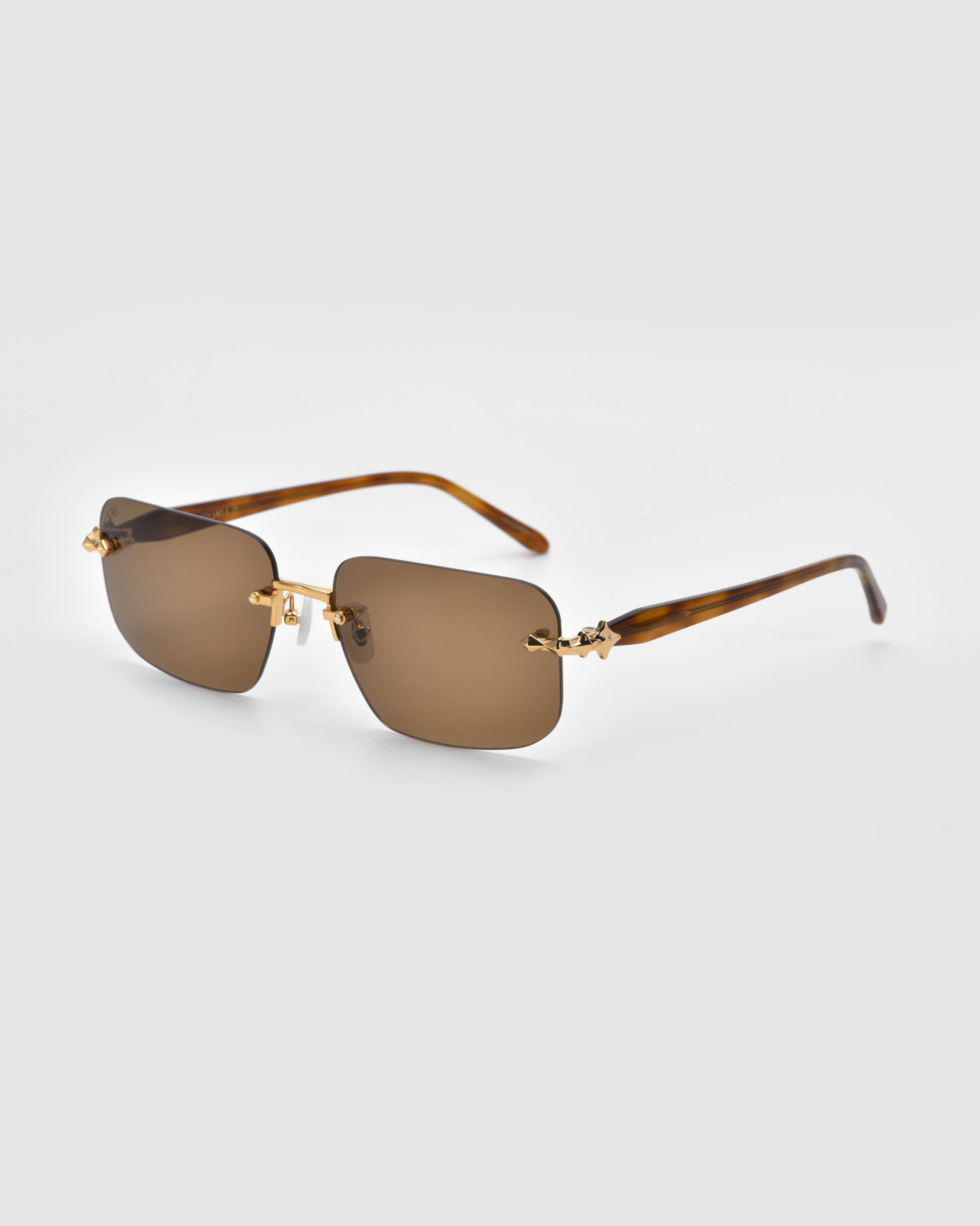 From the Rose Garden Collection by For Art's Sake®, the Edith sunglasses feature rimless, brown-tinted rectangular lenses with gold hinges and stylish brown tortoiseshell-patterned arms against a light gray backdrop.