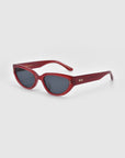 For Art's Sake® Lush red cat-eye sunglasses, crafted from premium materials, showcase dark lenses and small gold details on the arms, elegantly displayed against a plain white backdrop.