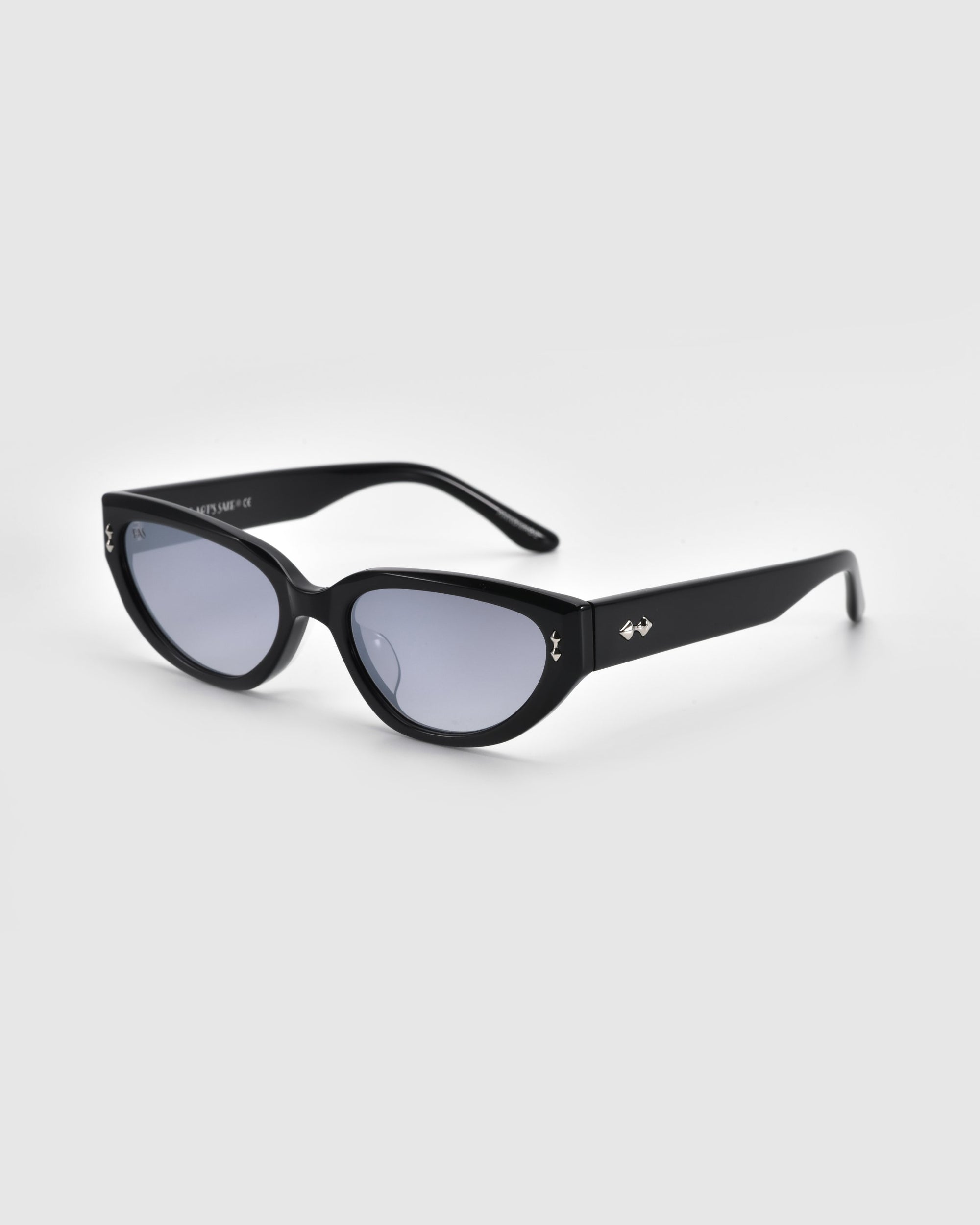 The Lush sunglasses from For Art's Sake® feature black, oval-shaped lenses on a white background, with sleek frames made of premium materials and small metallic accents on the temples.