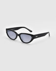 The Lush sunglasses from For Art's Sake® feature black, oval-shaped lenses on a white background, with sleek frames made of premium materials and small metallic accents on the temples.