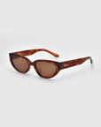 The Lush sunglasses by For Art's Sake® feature a cat-eye style with tortoiseshell frames, brown tinted lenses, and a stylized logo on the temples. Crafted from premium full acetate, they stand out against the light gray background.