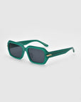 Fleur sunglasses by For Art's Sake® feature a sleek green acetate frame, dark lenses, and gold-accented temples against a plain light gray background.