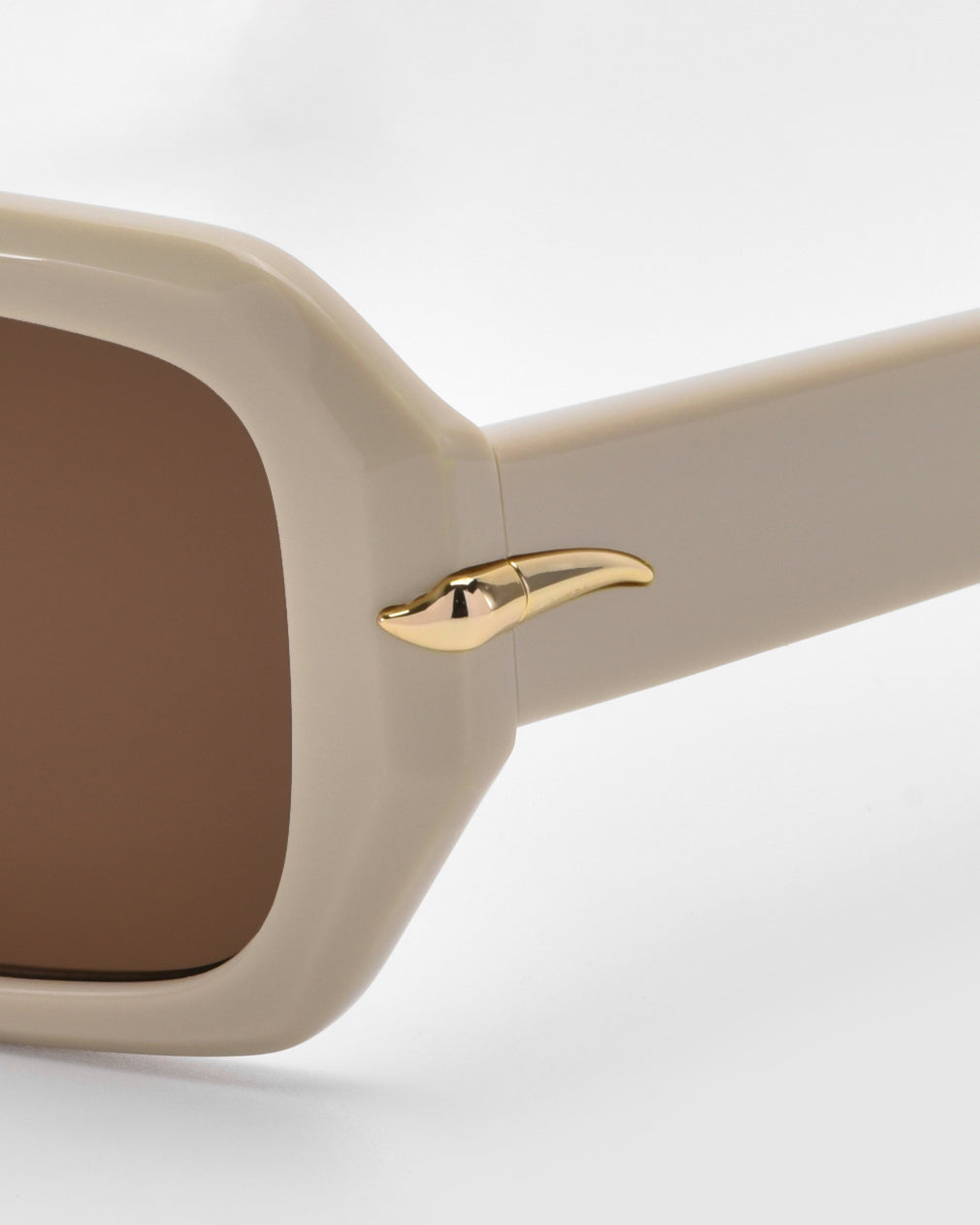 The Fleur sunglasses by For Art's Sake® feature beige acetate frames, square brown lenses, and gold side temple accents. Their luxurious yet versatile design makes them perfect for everyday wear while exuding subtle elegance against a light background.