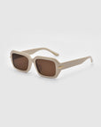 The Fleur by For Art's Sake® are beige square sunglasses with brown lenses and gold temple details, elegantly designed with an acetate frame, shown on a light gray background.